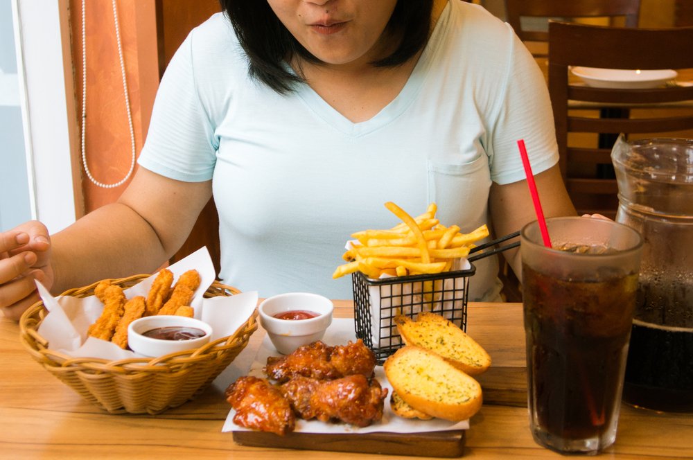 Mujer comiendo comida chatarra. | Foto: Shutterstock