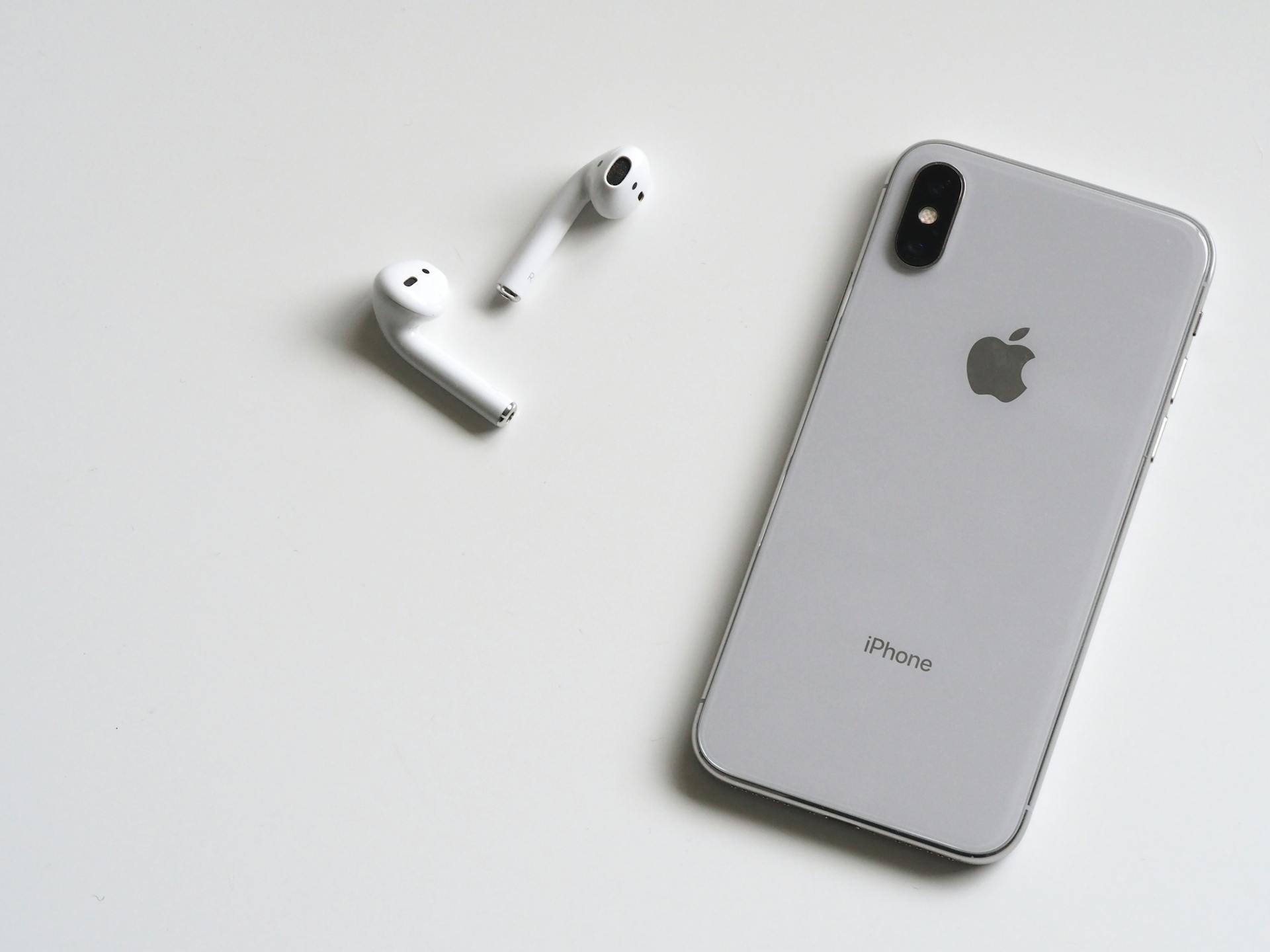 Un iPhone X plateado con Airpods | Fuente: Pexels