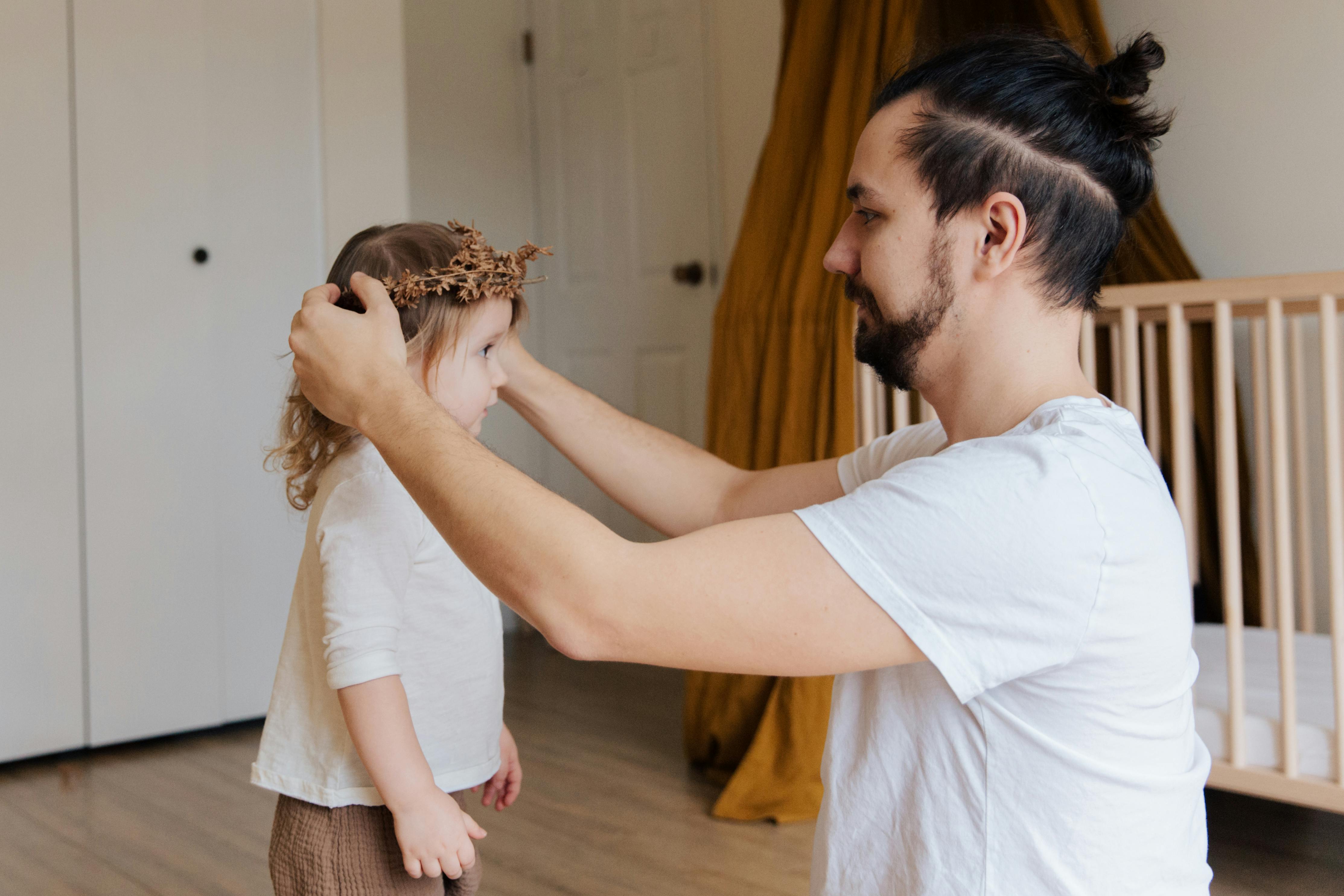 Un padre adornando el pelo de su hija | Fuente: Pexels