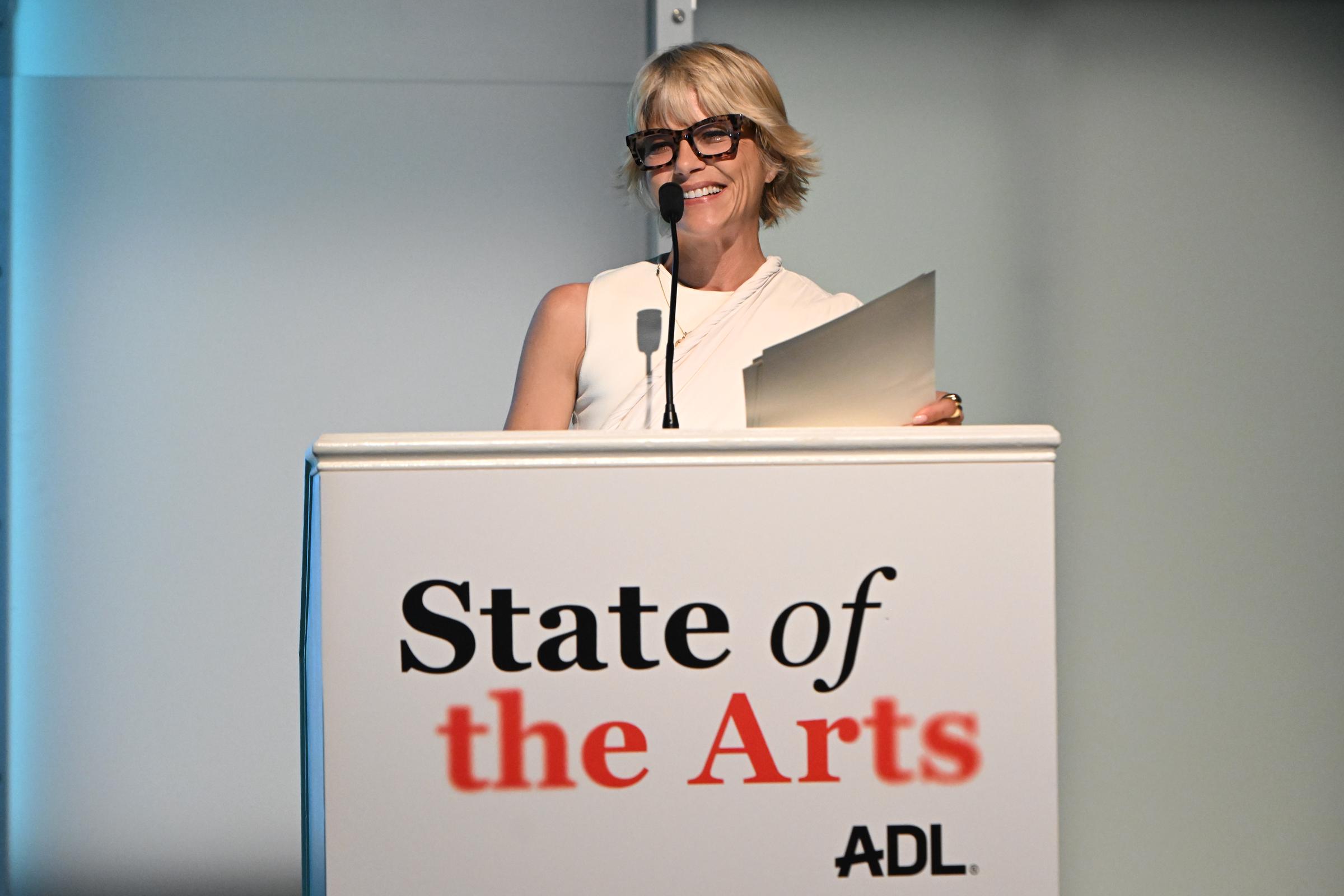 Selma Blair sonríe con calidez mientras habla desde el podio durante el evento State of the Arts: An Evening at The Jewish Museum de la ADL el 1 de octubre de 2026, en Nueva York. Lleva un top marfil sin mangas de cuello alto combinado con unos anteojos llamativos de carey, y sostiene sus notas mientras se dirige al público. | Fuente: Getty Images