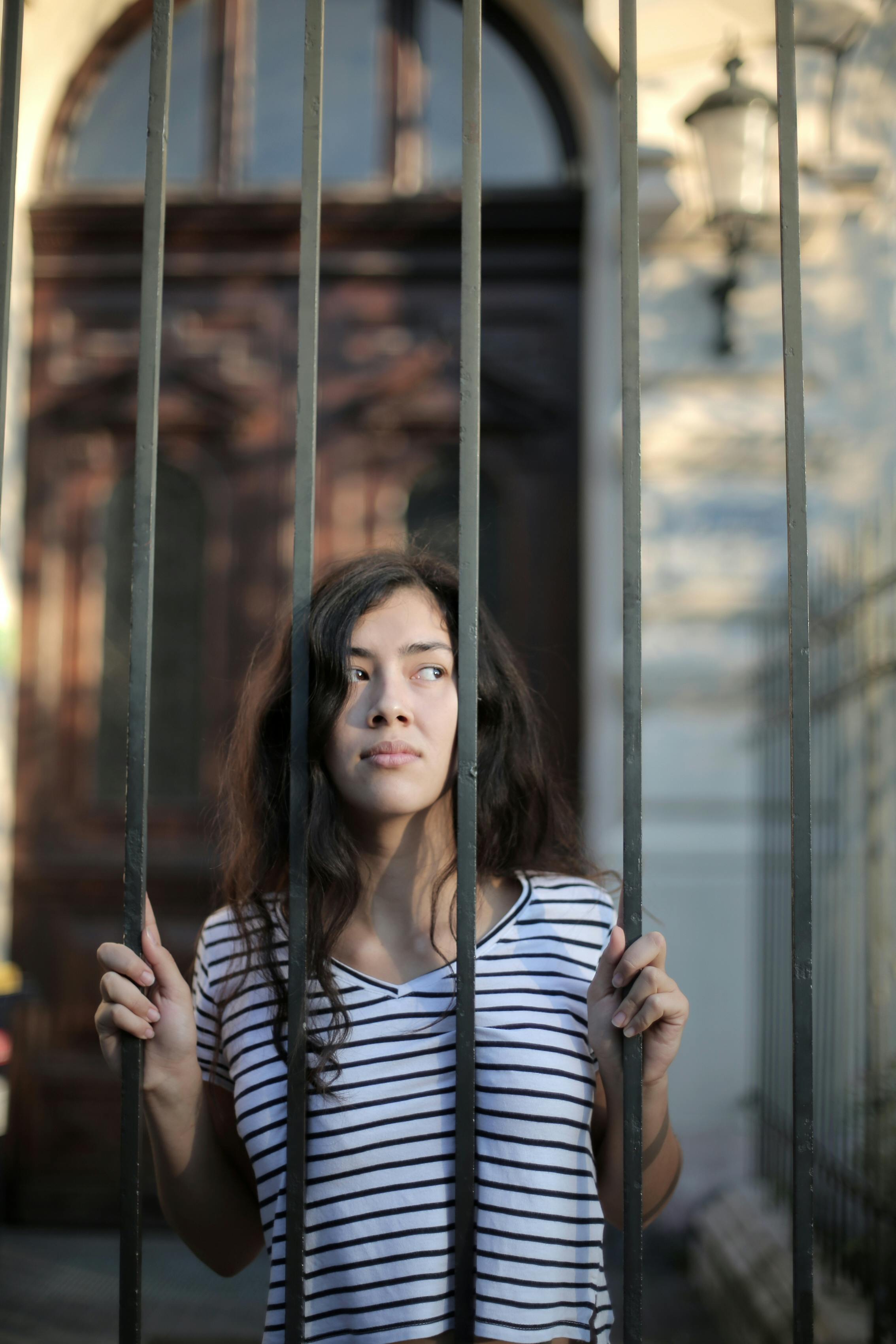 Una mujer mirando a través de una verja | Fuente: Pexels