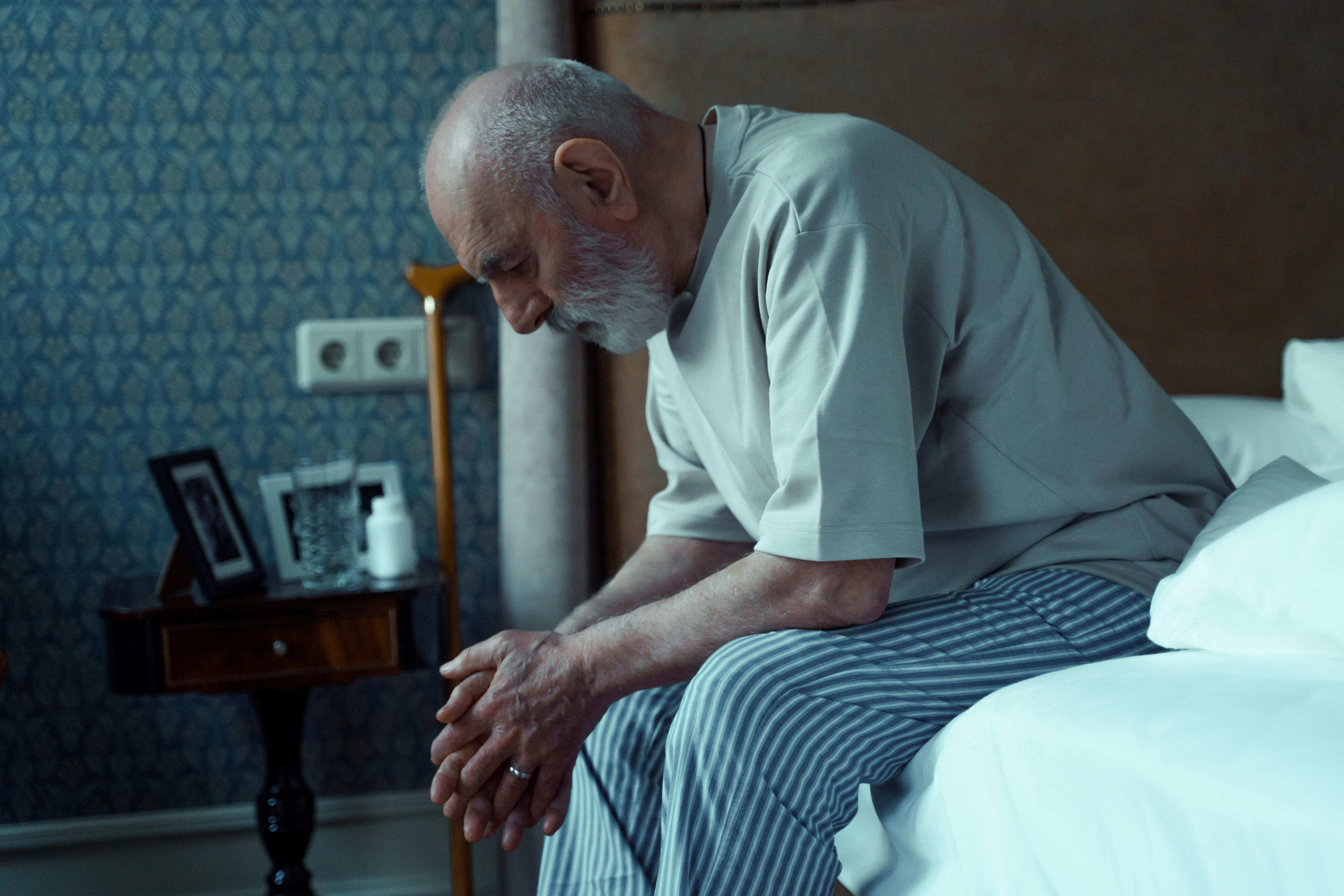 Un hombre de aspecto enfermo sentado en una cama | Fuente: Pexels