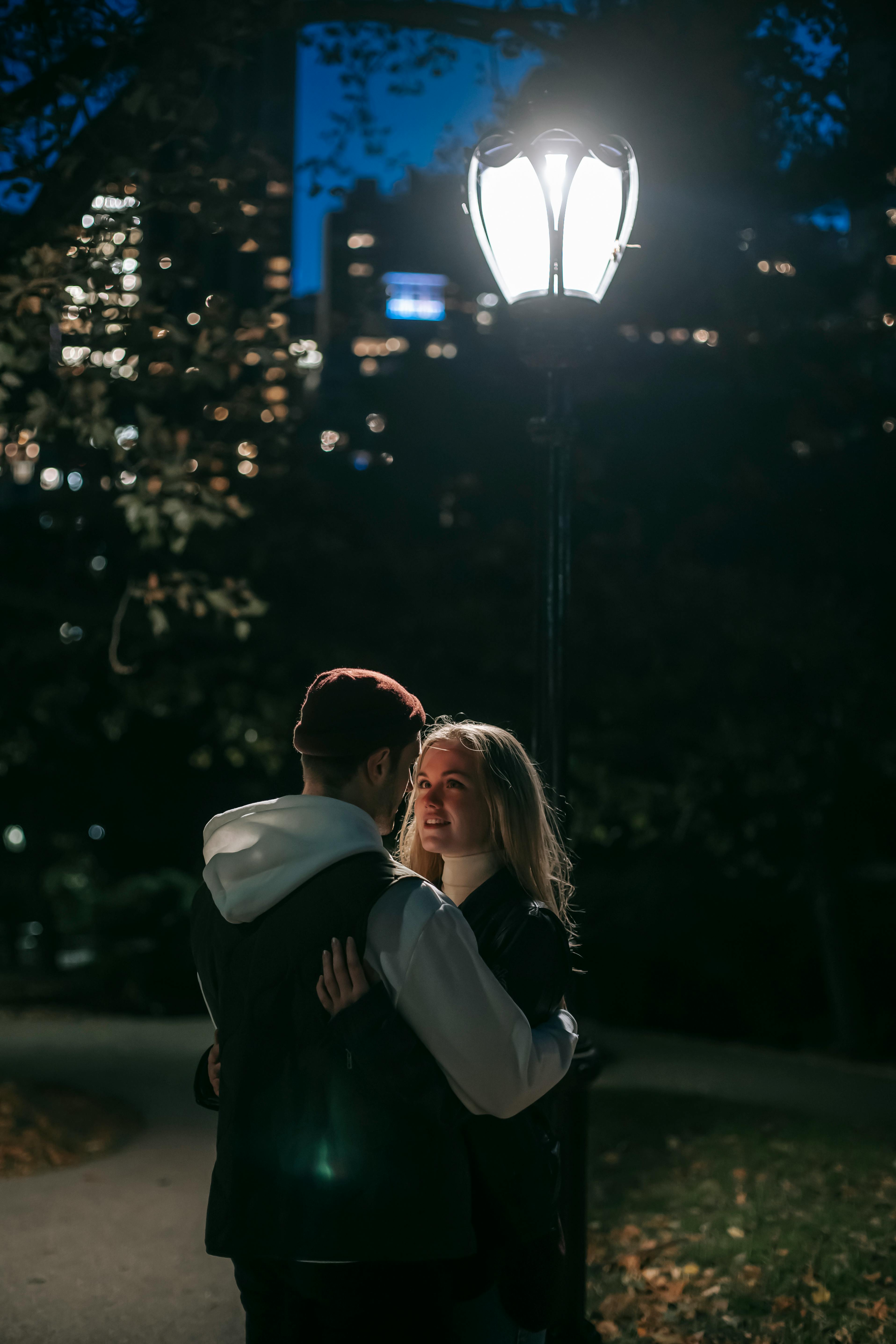 Pareja abrazándose en un parque por la noche | Foto: Pexels