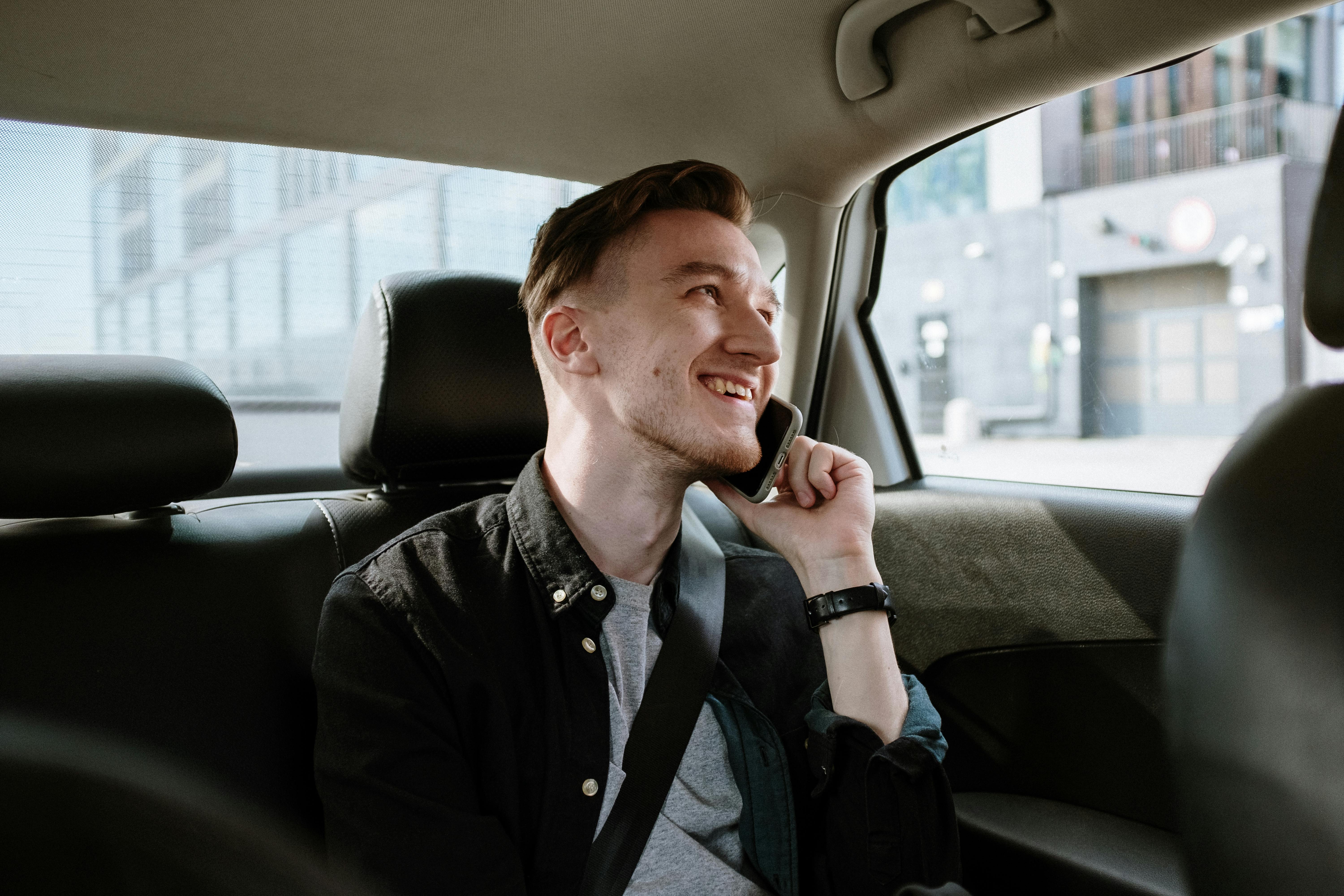 Un hombre feliz hablando por teléfono mientras viaja en automóvil | Foto: Pexels