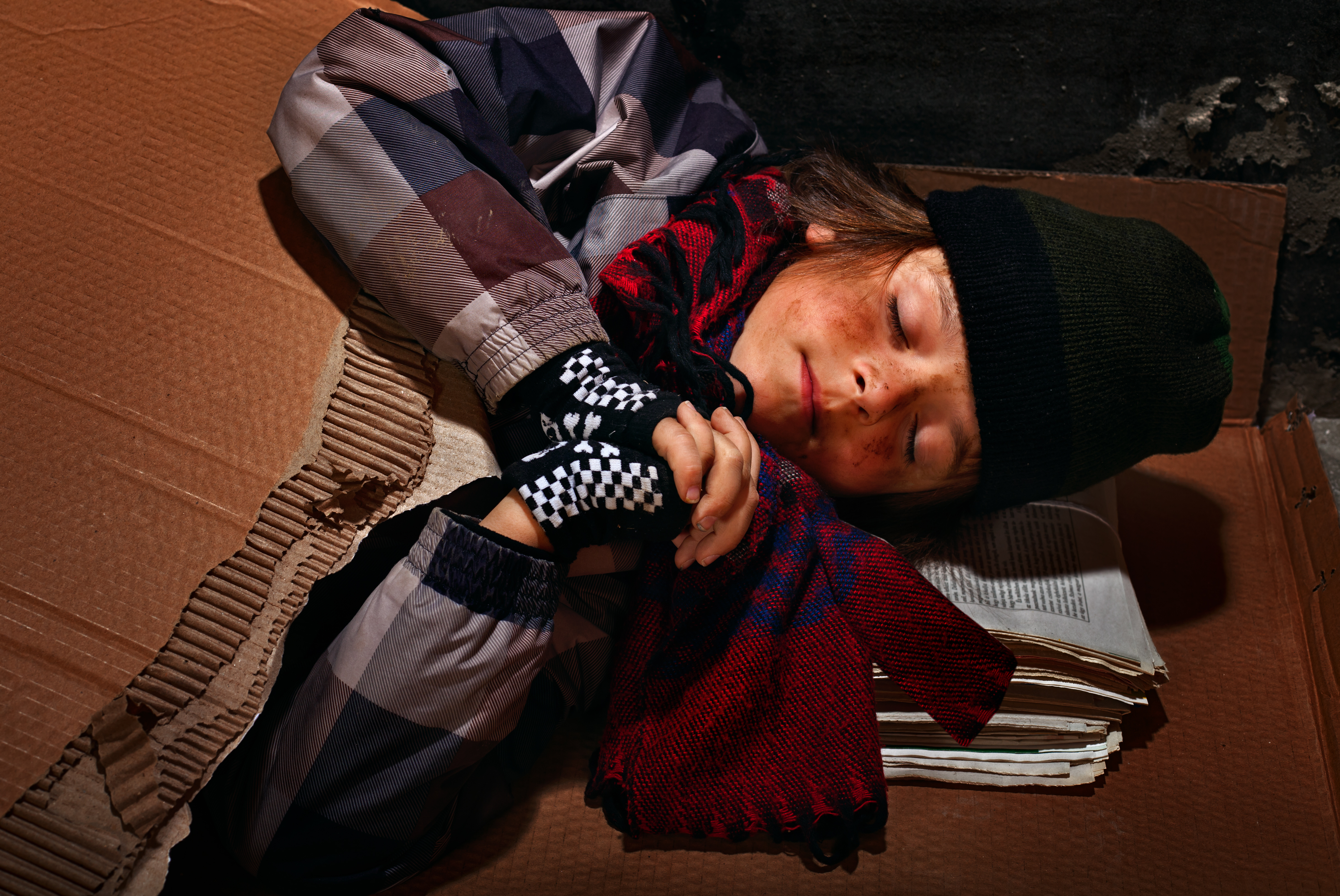 Niño pobre mendigo preparándose para dormir en la calle | Fuente: Shutterstock.com