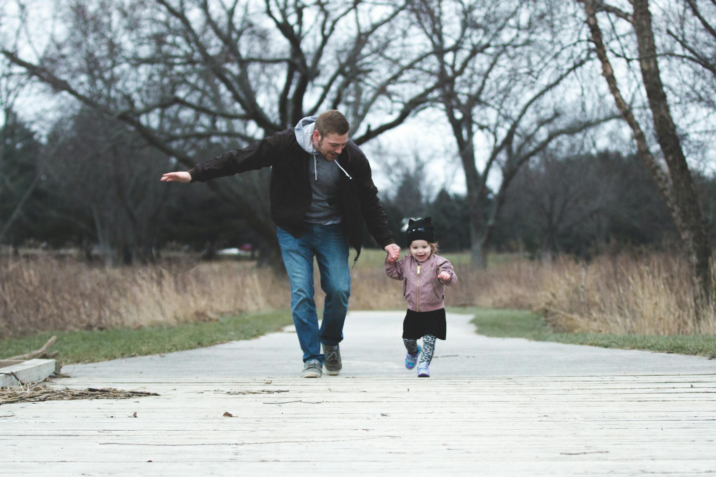 Hombre corre con su hija pequeña | Fuente: Pexels