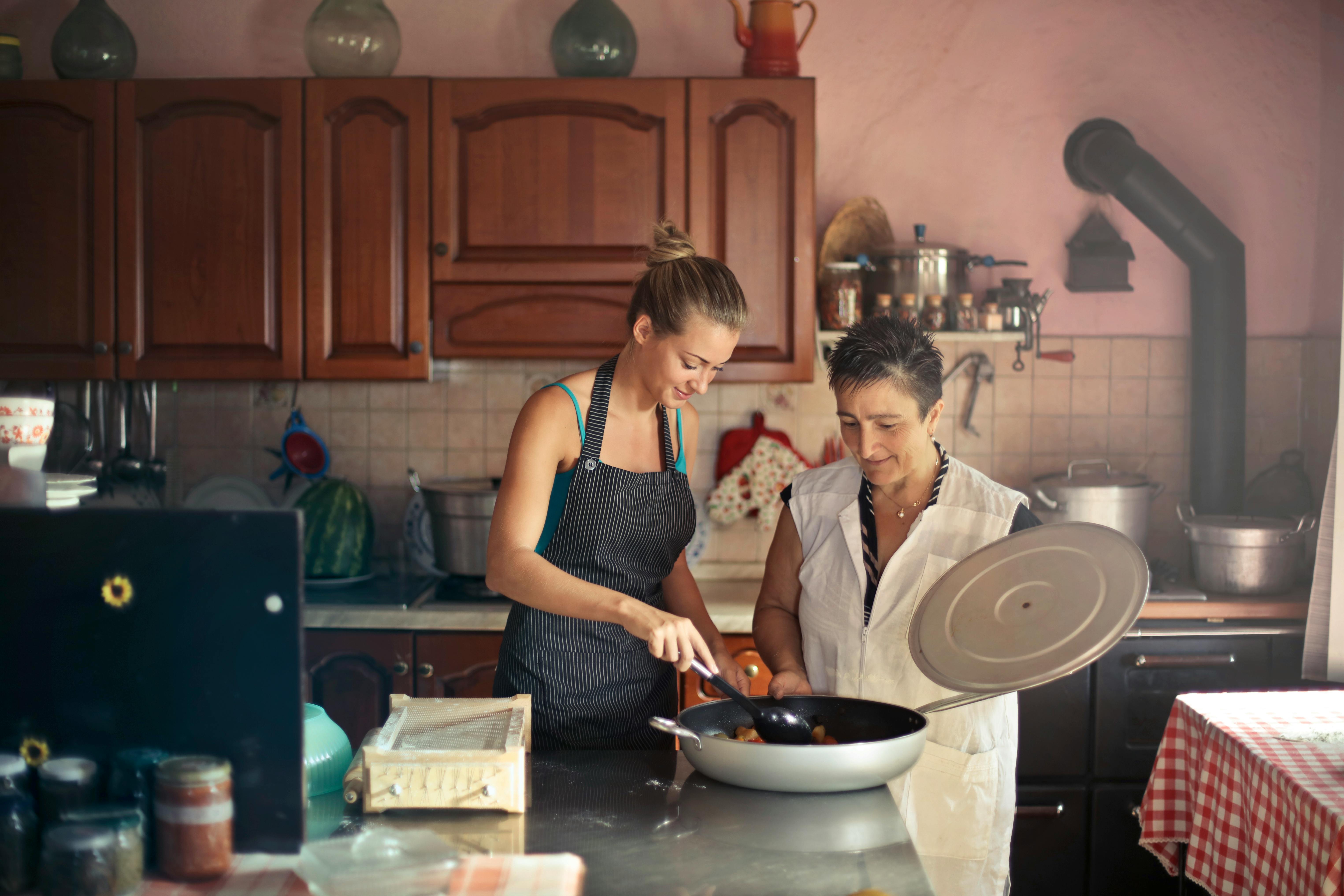 Una mujer joven feliz y otra mayor trabajando en la cocina | Fuente: Pexels