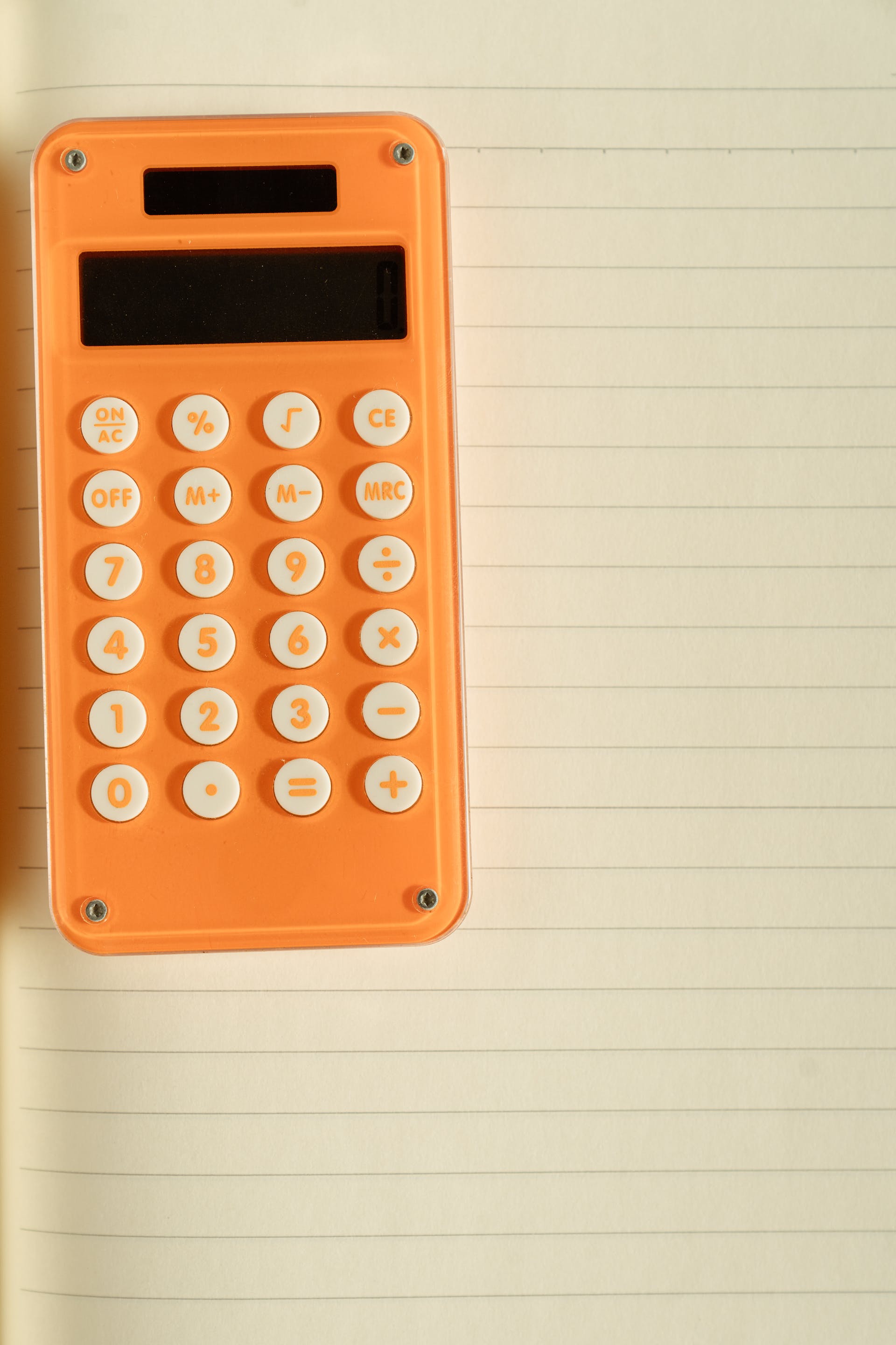 Una calculadora naranja sobre papel blanco | Foto: Pexels