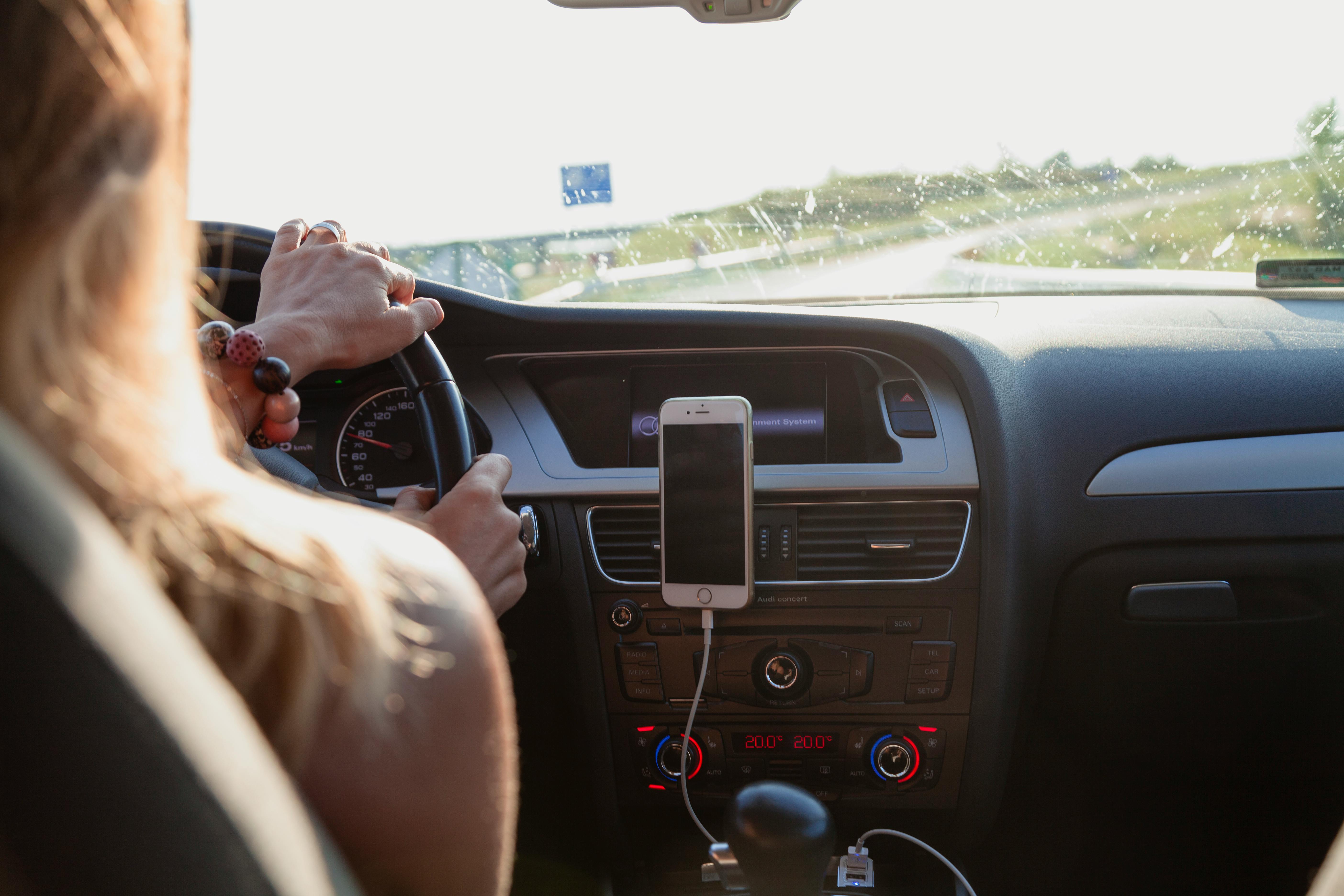 Una mujer conduciendo con el teléfono acoplado en su automóvil | Foto: Pexels