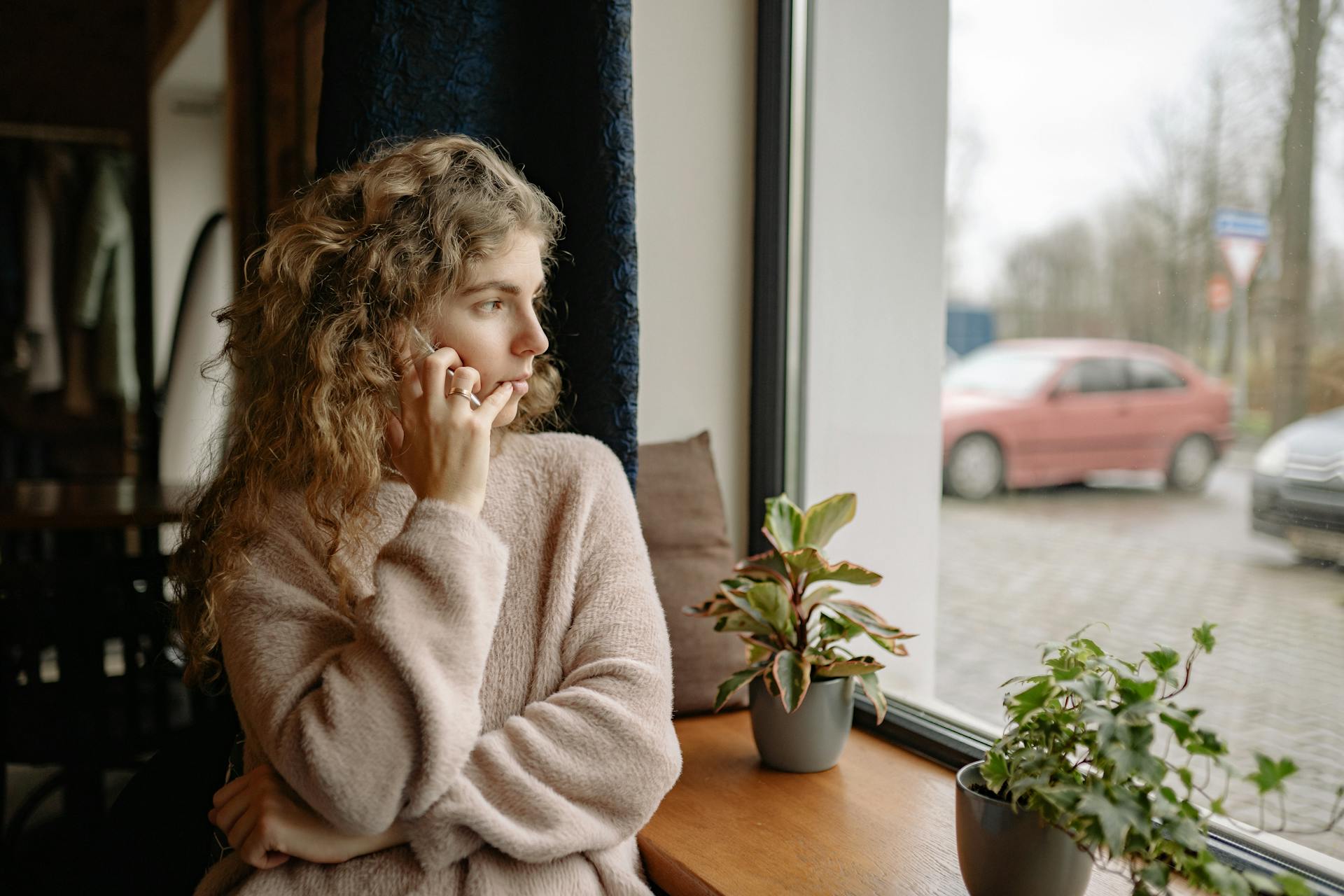 Una mujer hablando por teléfono mientras mira por la ventana | Fuente: Pexels