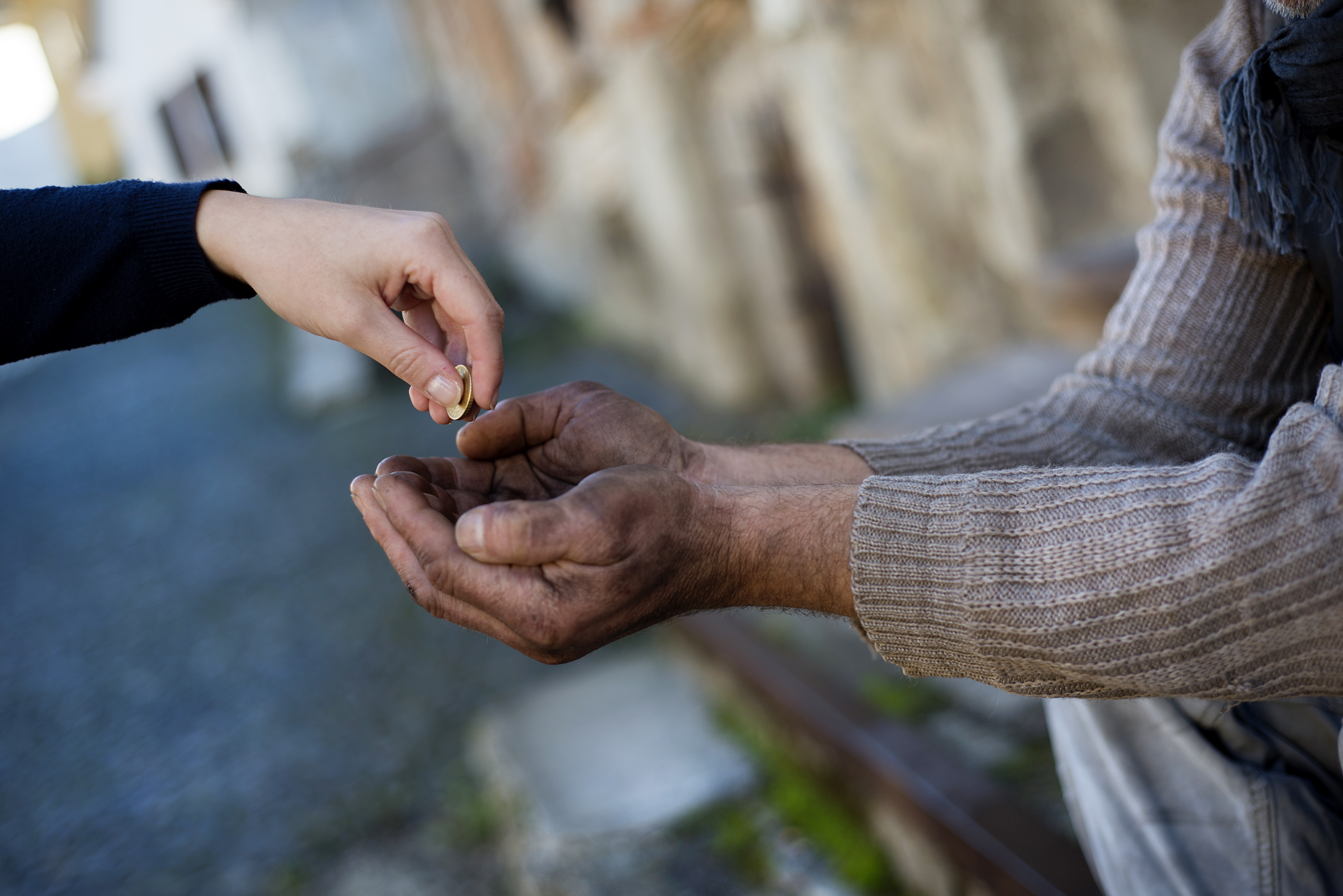 Alguien dando monedas a persona sin hogar | Foto: Shutterstock