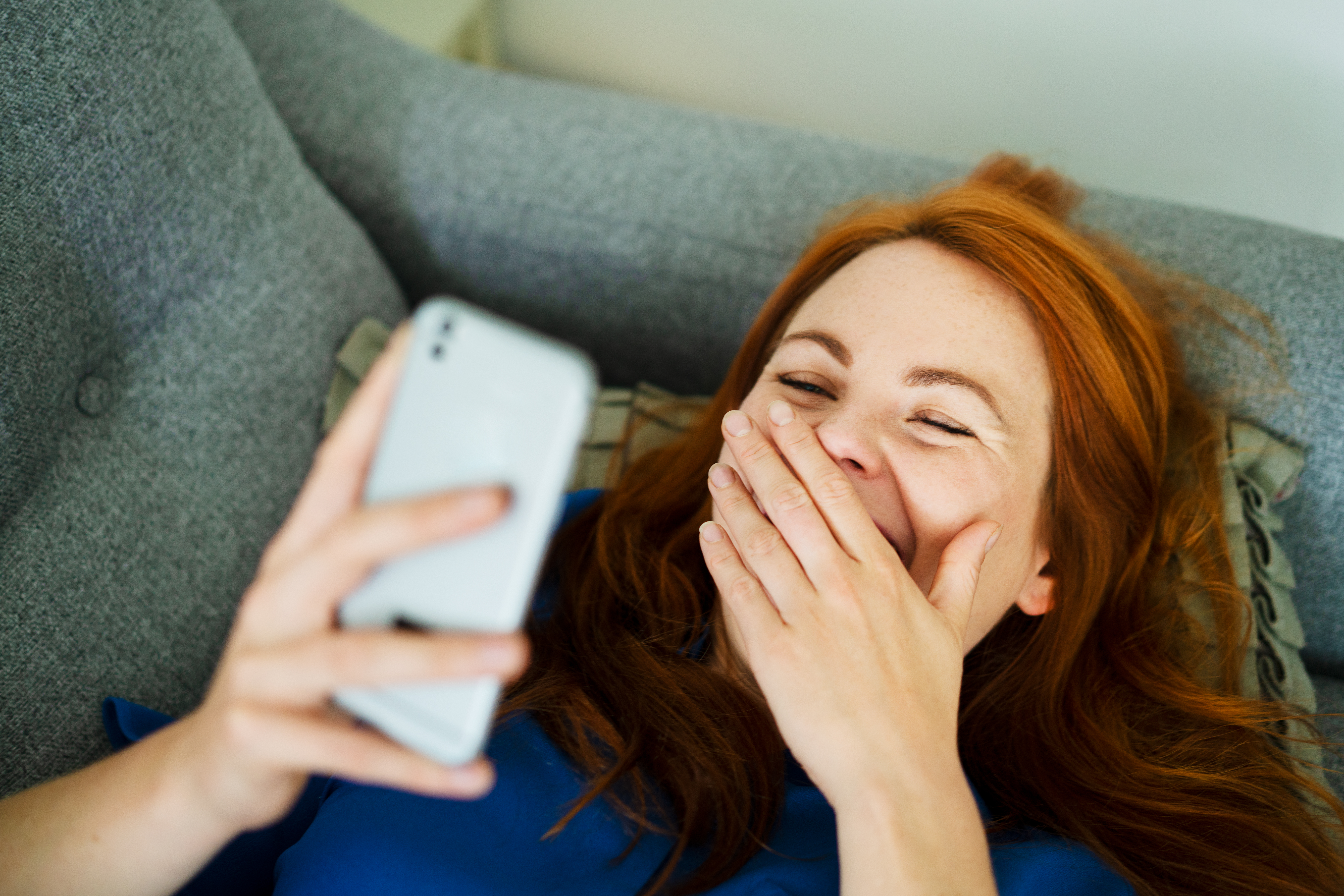 Una mujer ríe mientras mira su teléfono | Foto: Getty Images