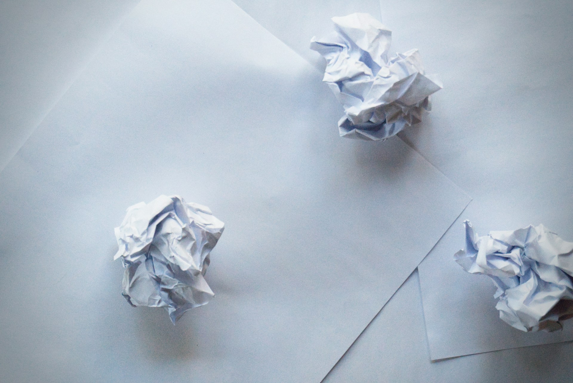 Bolas de papel arrugado y hojas de papel sobre una superficie | Fuente: Unsplash