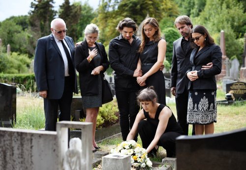 Familia colocando flores en la tumba de un ser querido. | Fuente: Shutterstock.