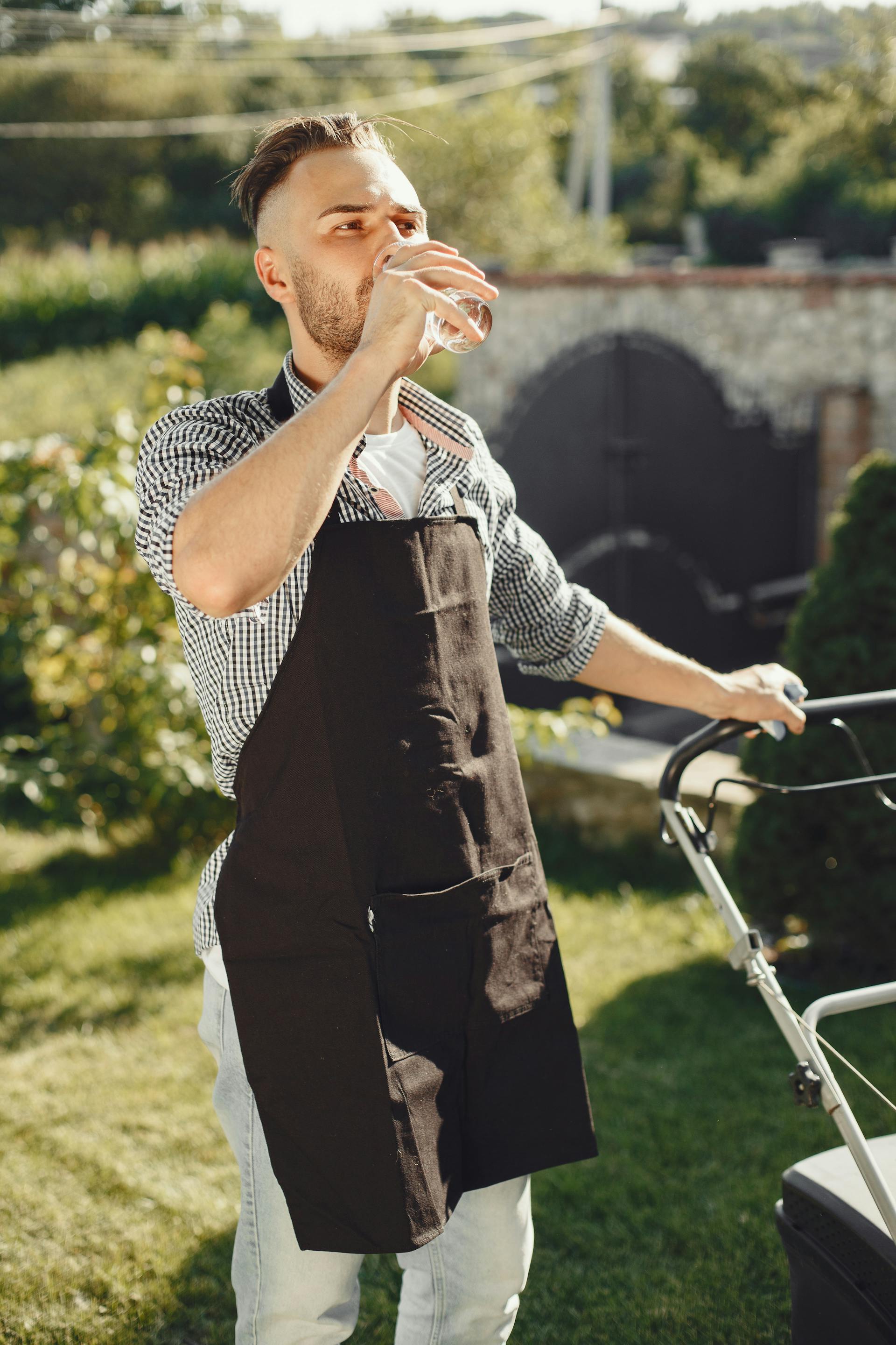 Un hombre bebiendo agua de pie en su jardín | Fuente: Pexels