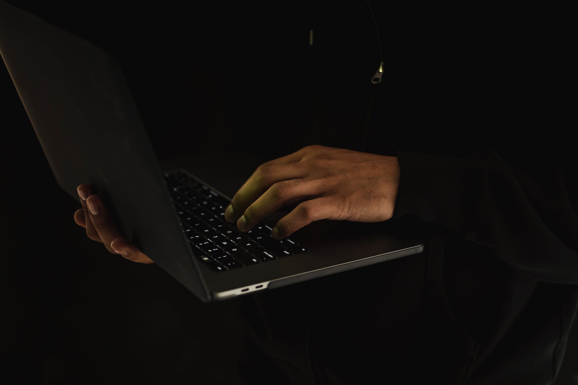 Una persona utilizando un portátil en la oscuridad | Fuente: Pexels