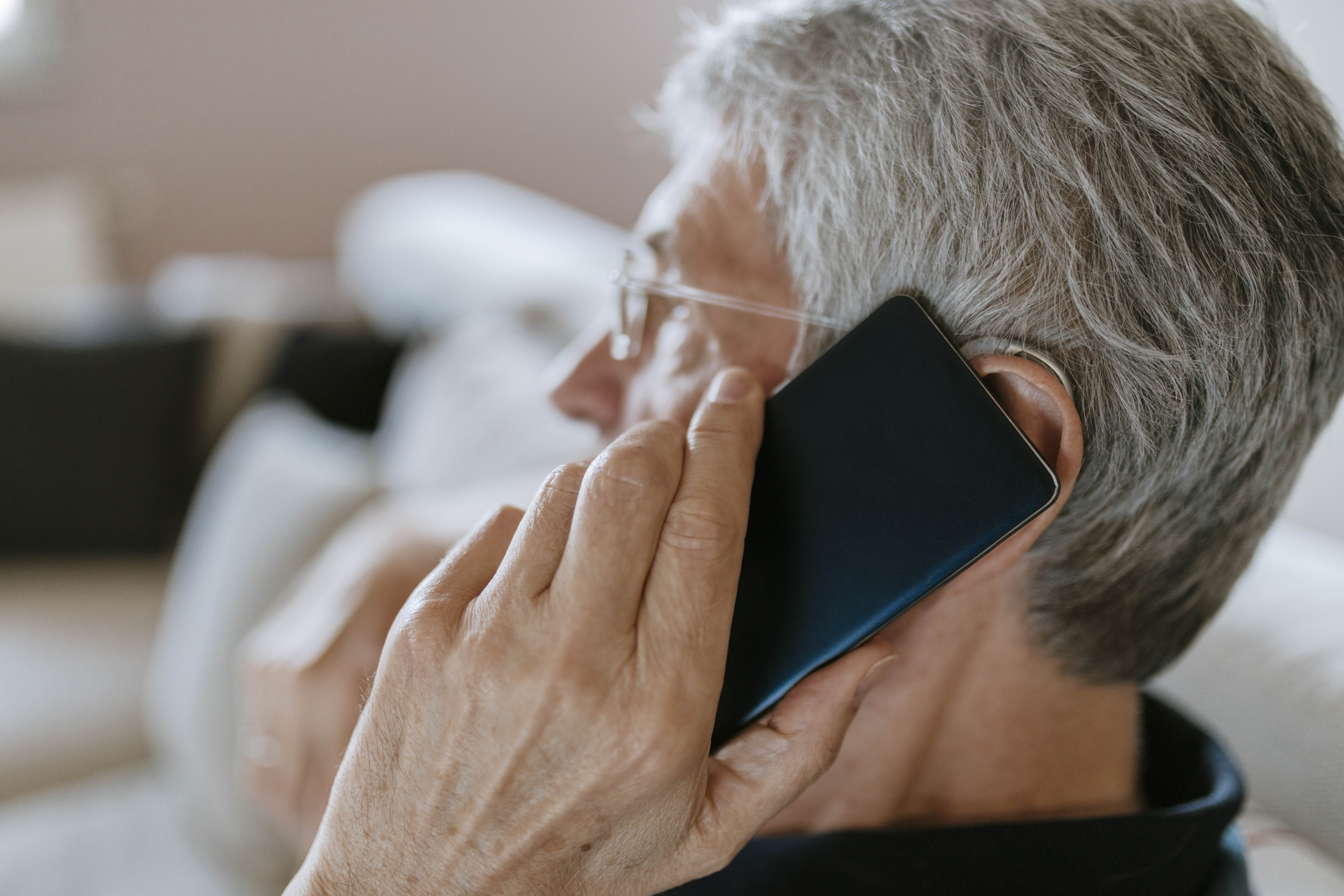 Hombre mayor con audífono en el móvil | Fuente: Getty Images