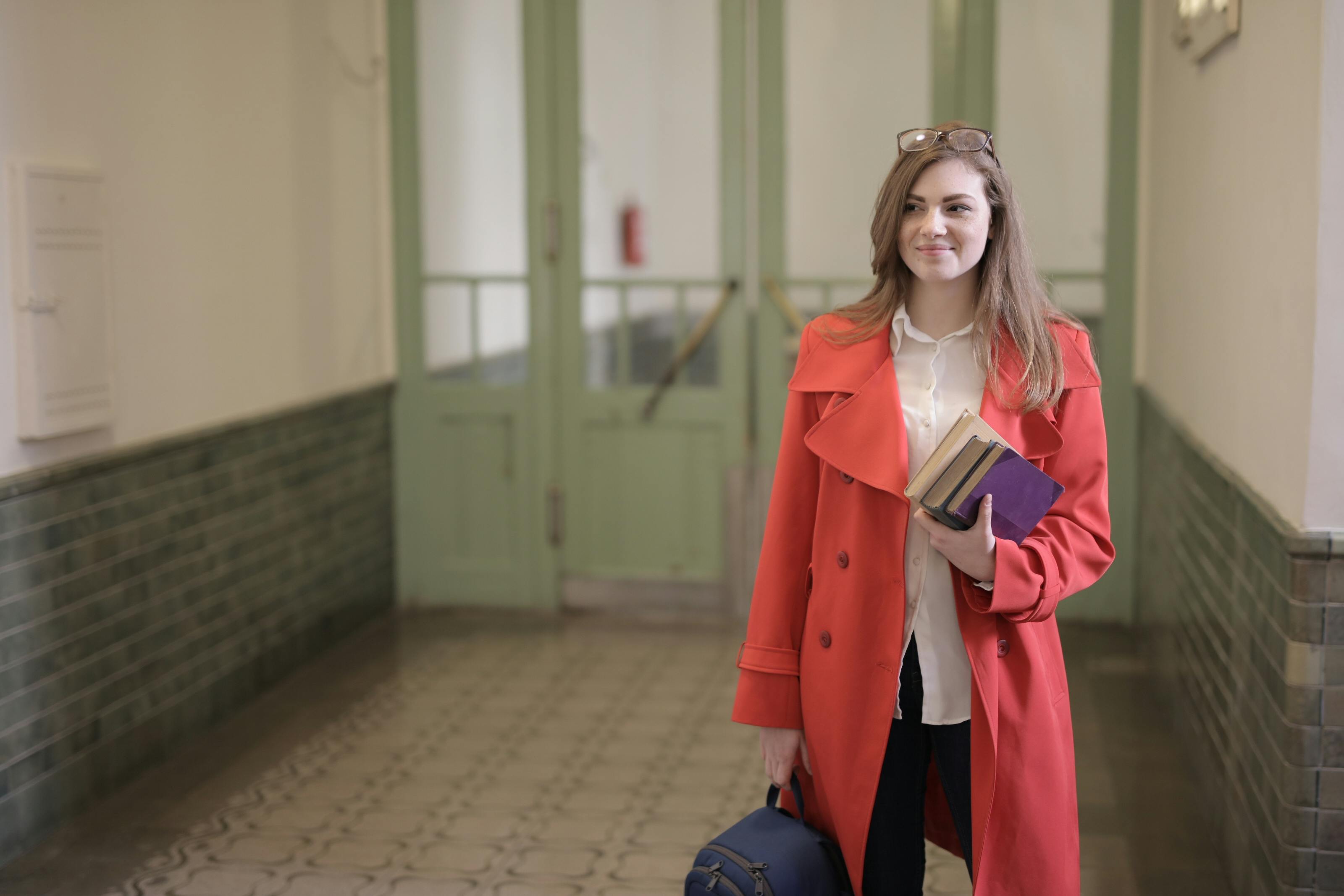 Una estudiante con libros y una mochila en la mano | Fuente: Pexels