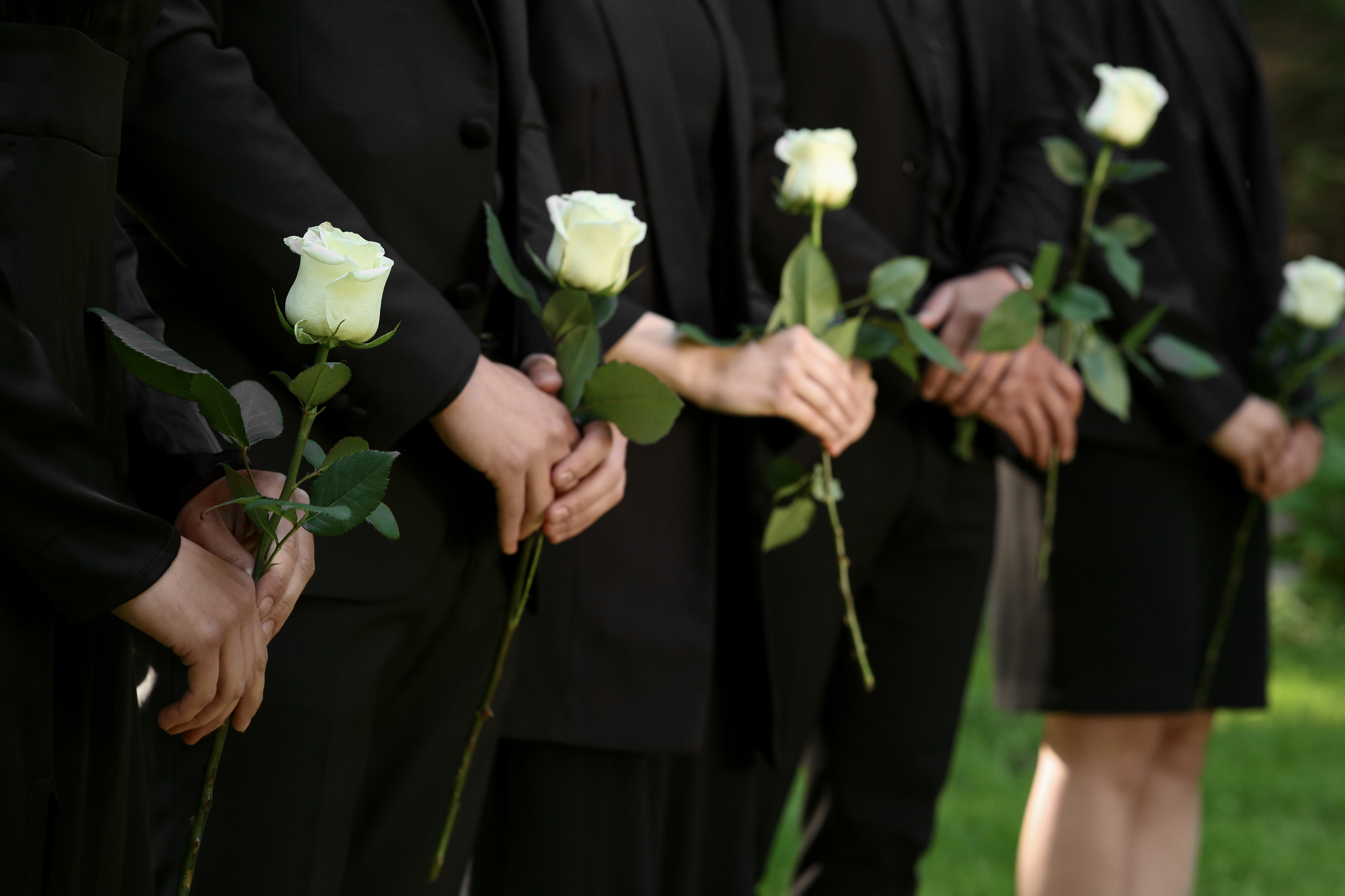 Familia con rosas blancas en un funeral | Foto: Shutterstock
