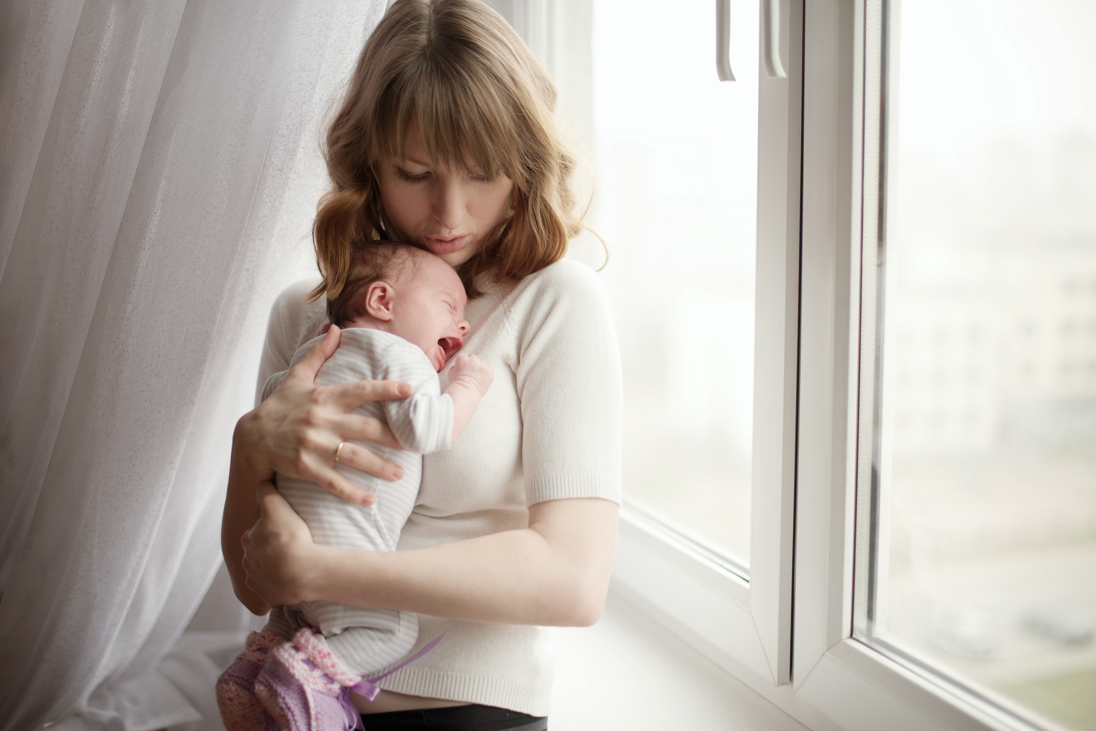 Mujer con niño llorando en brazos | Fuente: Shutterstock.com