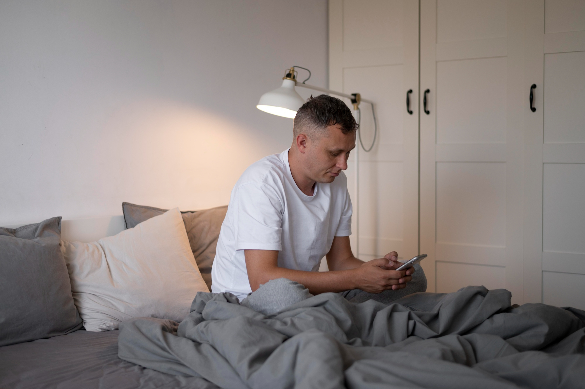 Hombre mirando un teléfono en la cama | Foto: Freepik