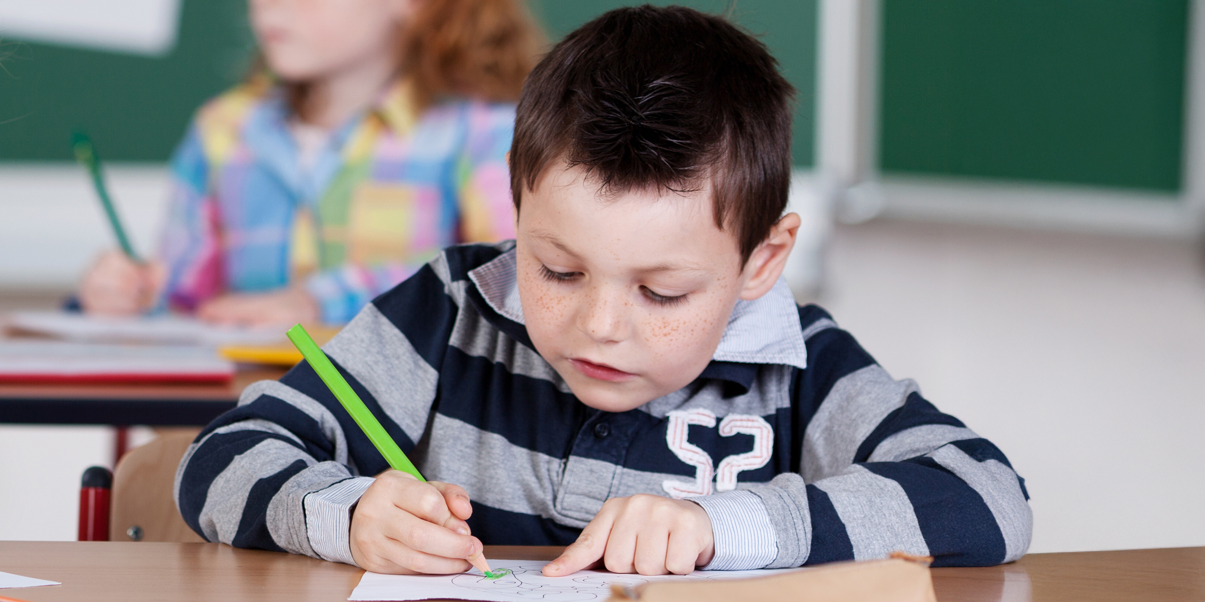 Un niño haciendo un dibujo en clase | Fuente: Shutterstock