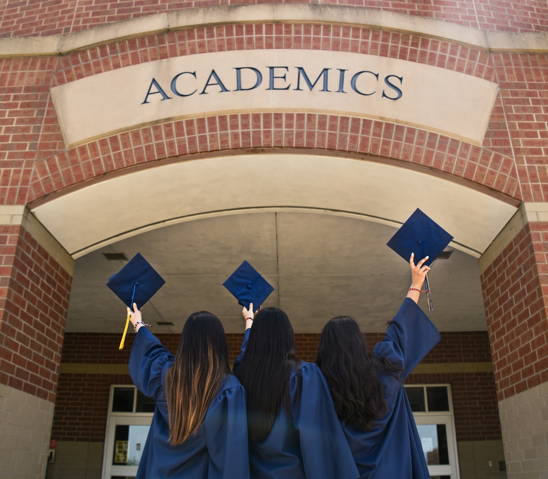 Jóvenes de pie frente a un edificio con sus togas de graduación | Fuente: Unsplash