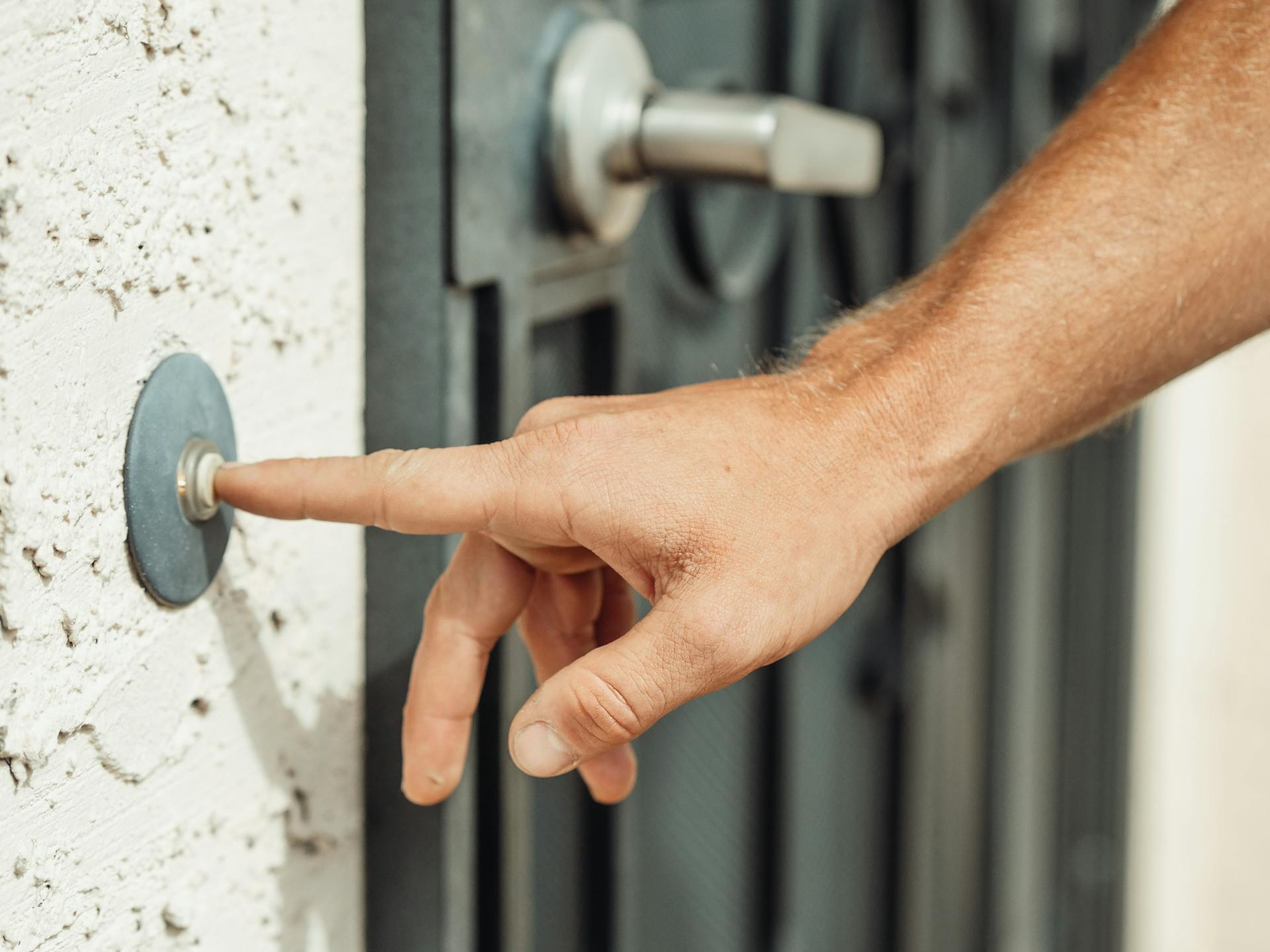 Primer plano de un hombre pulsando un timbre cerca de una puerta | Fuente: Pexels