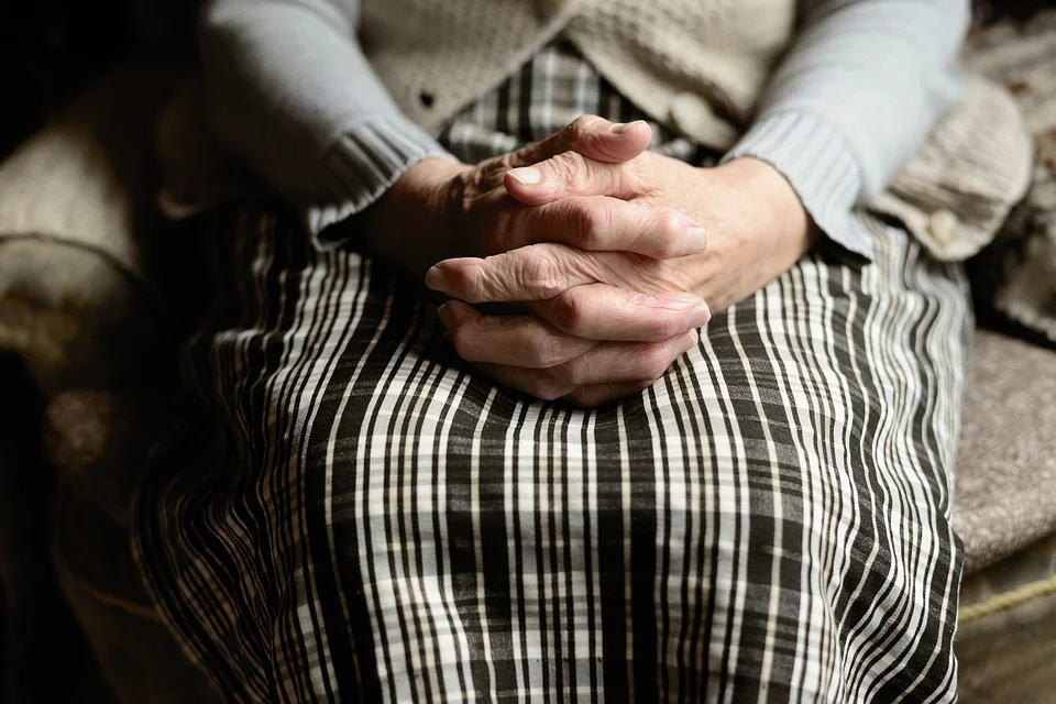 Mujer adulta mayor sentada con las manos sobre las piernas. | Foto: Pixabay