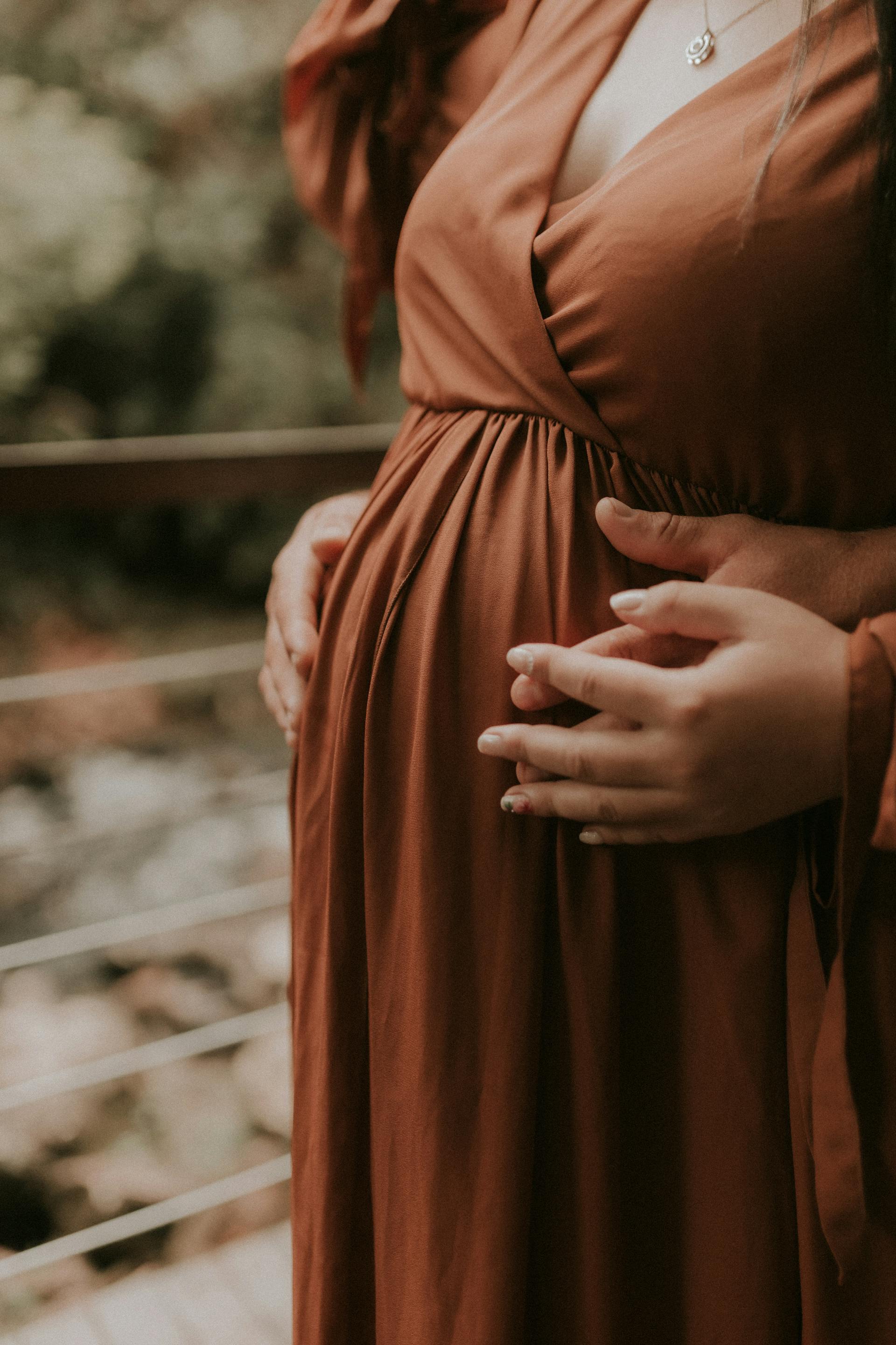 Una pareja cogida de la mano mientras toca la barriga de la embarazada | Fuente: Pexels