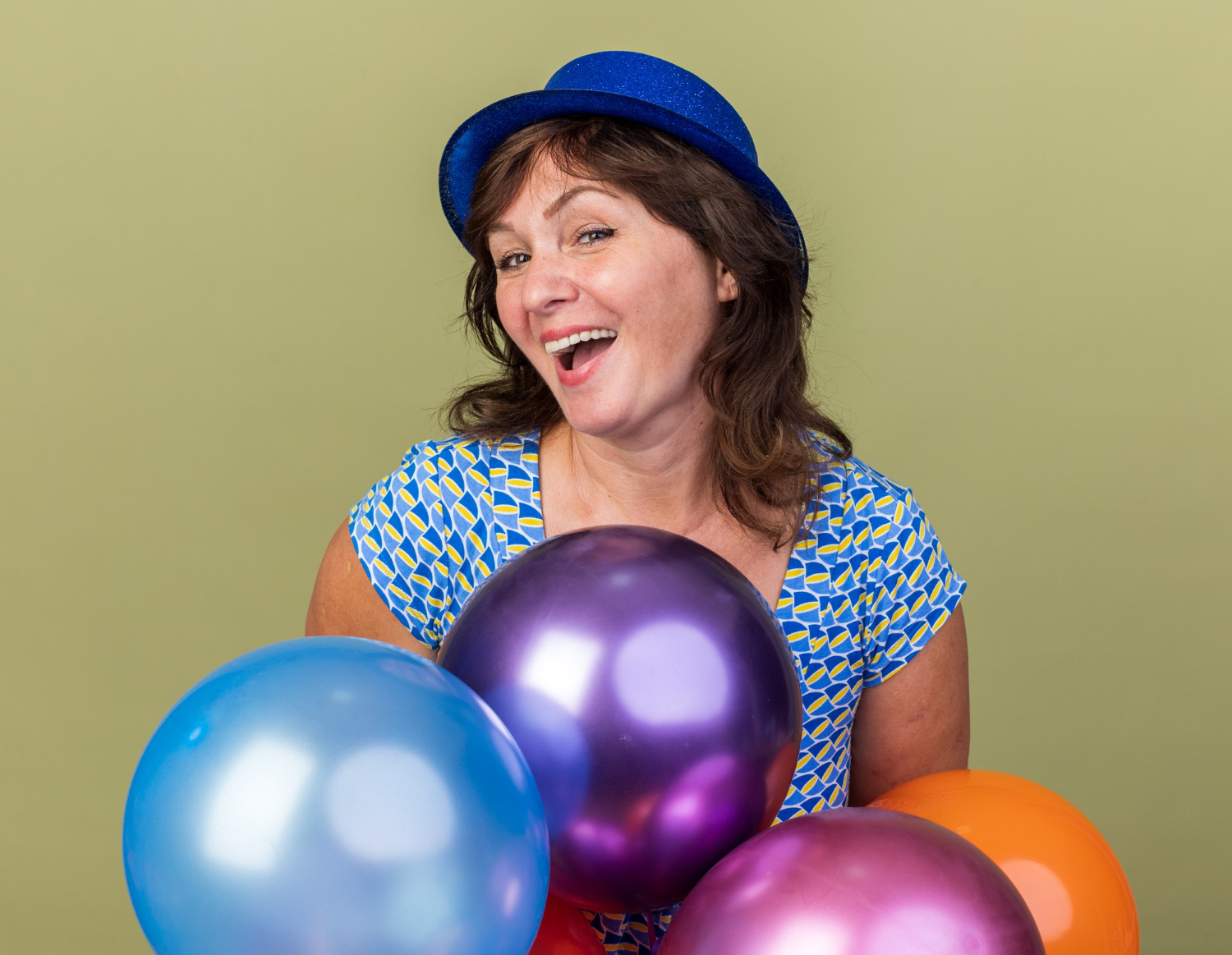 Una alegre mujer de mediana edad sosteniendo globos de colores | Fuente: Freepik