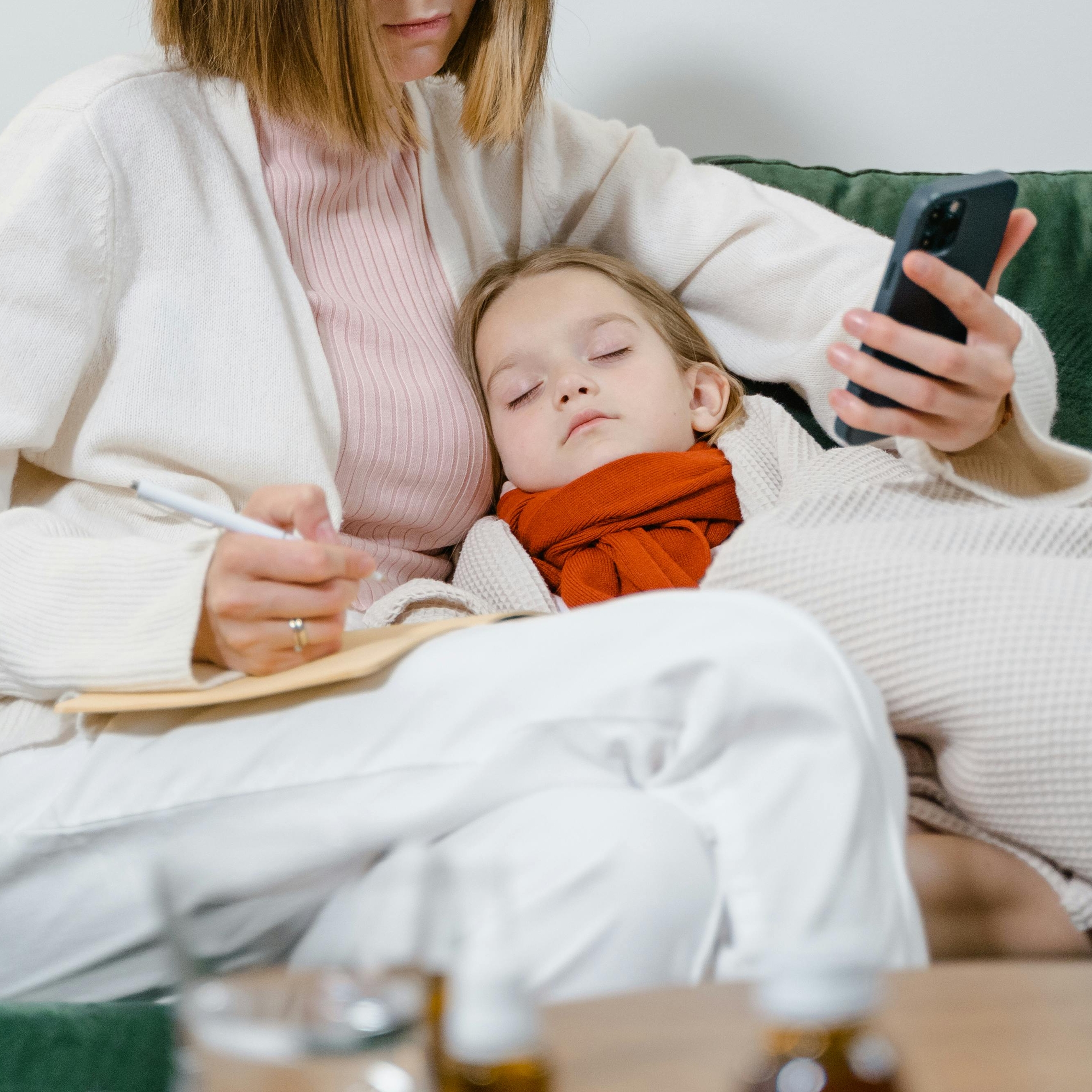 Una mujer cuida a un niño enfermo mientras toma notas | Fuente: Pexels