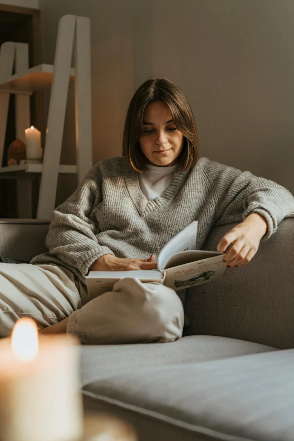 Una mujer leyendo un libro en un sofá | Fuente: Pexels