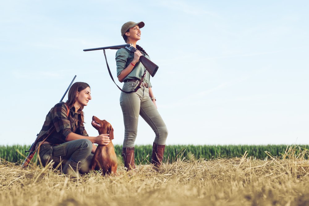 Mujeres armadas junto a un perro paradas sobre el pasto. | Foto: Getty Images