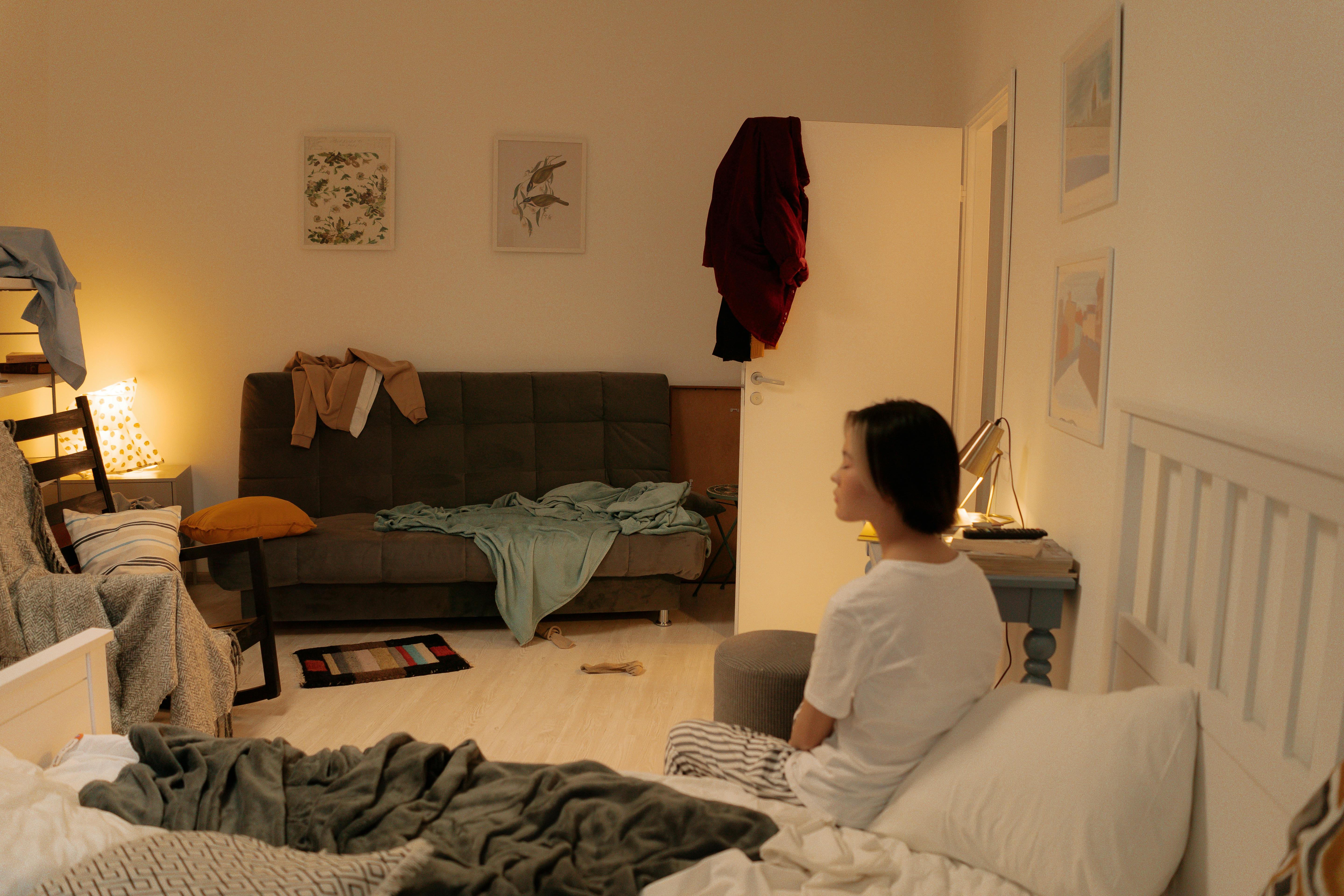 Dormitorio desordenado y mujer sentada en la cama | Foto: Pexels