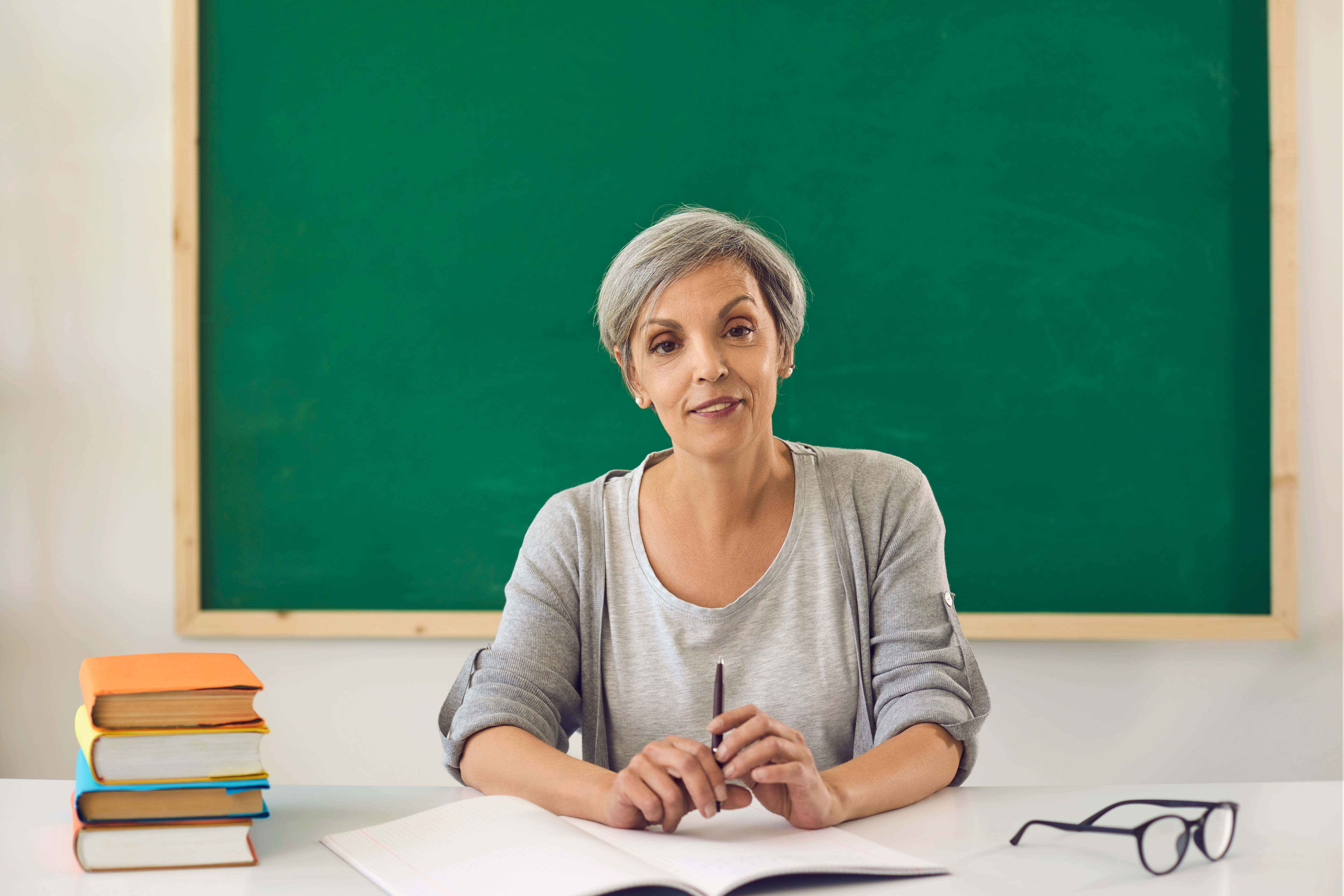 Profesora sonriendo desde su mesa | Foto: Shutterstock