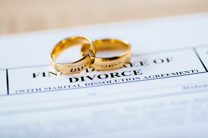 Anillos de bodas de oro sobre un documento de divorcio. | Foto: Shutterstock