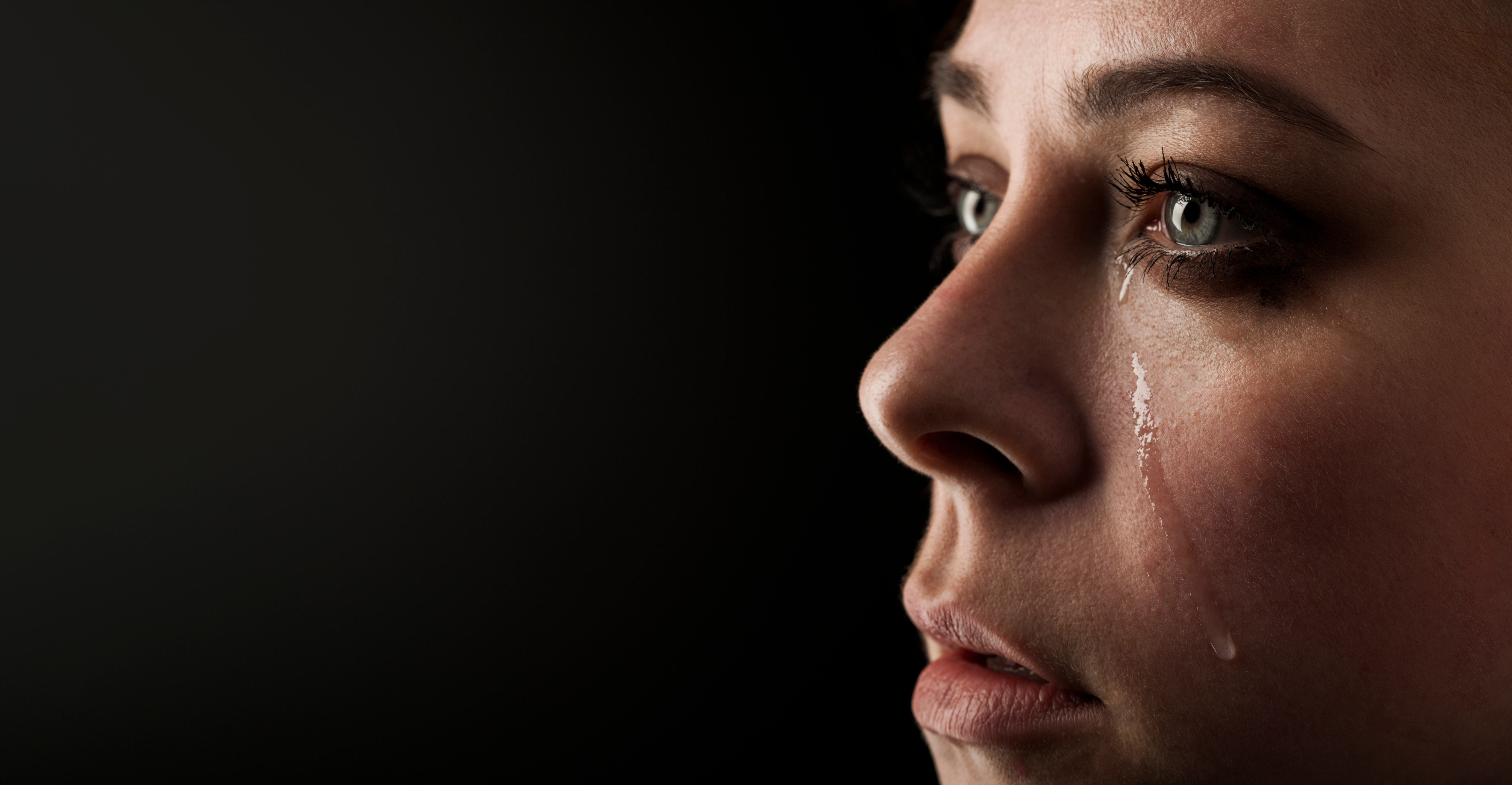 Hermosa chica llora sobre fondo negro. | Fuente: Shutterstock