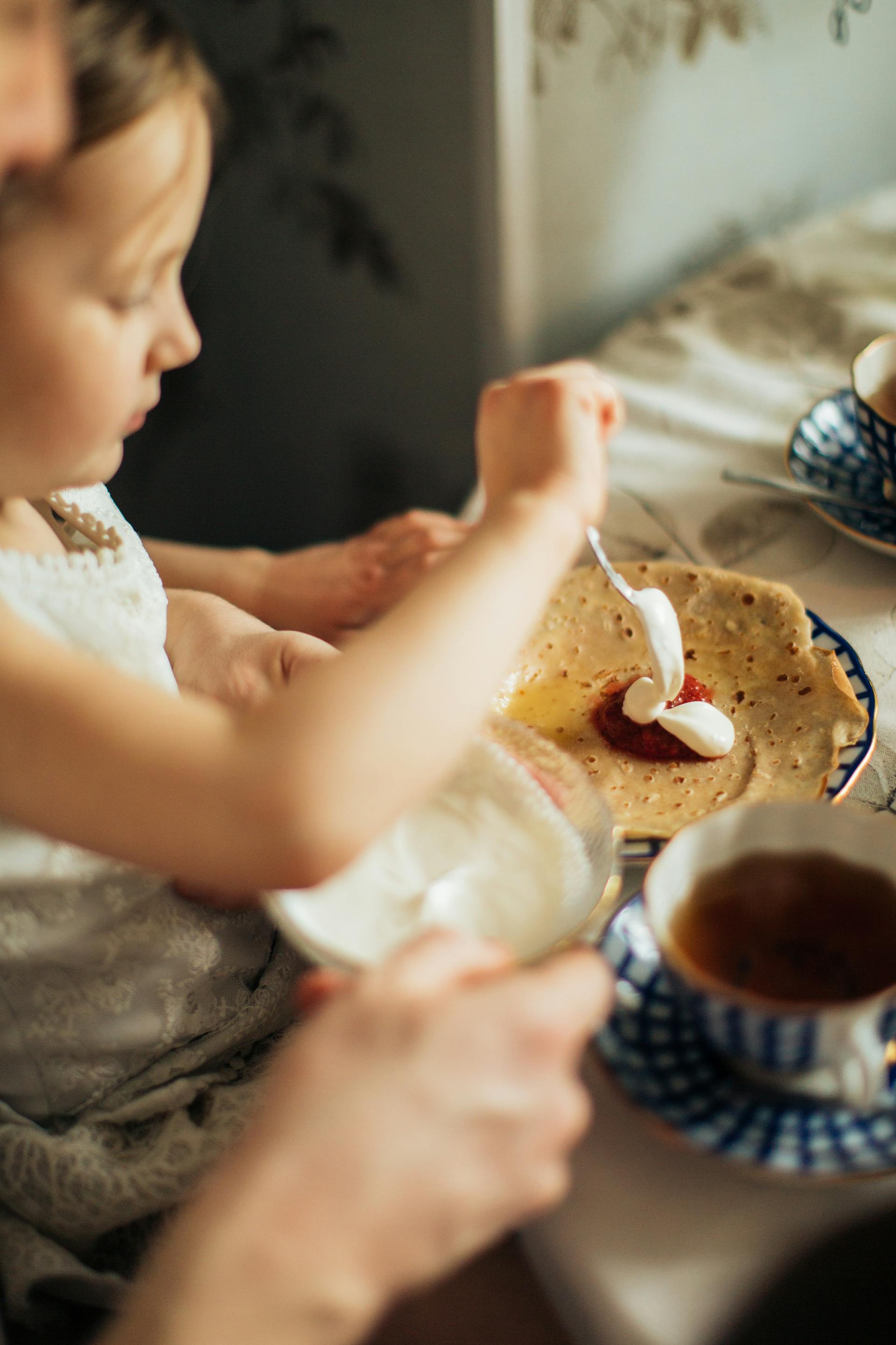 Una joven untando mermelada y nata en un crepe | Fuente: Pexels