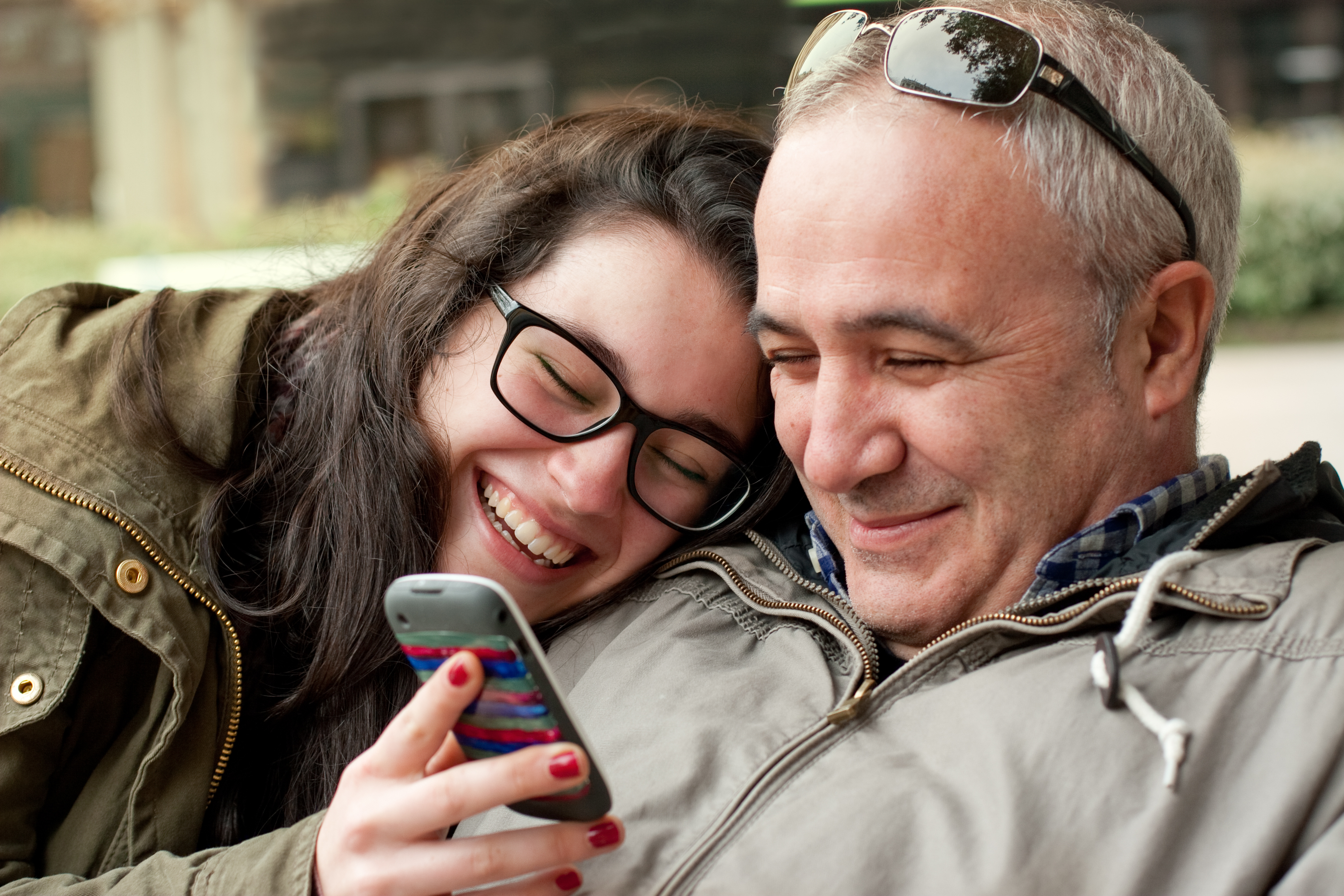 Un hombre estrechando lazos con su hija mientras mira su teléfono | Foto: Shutterstock