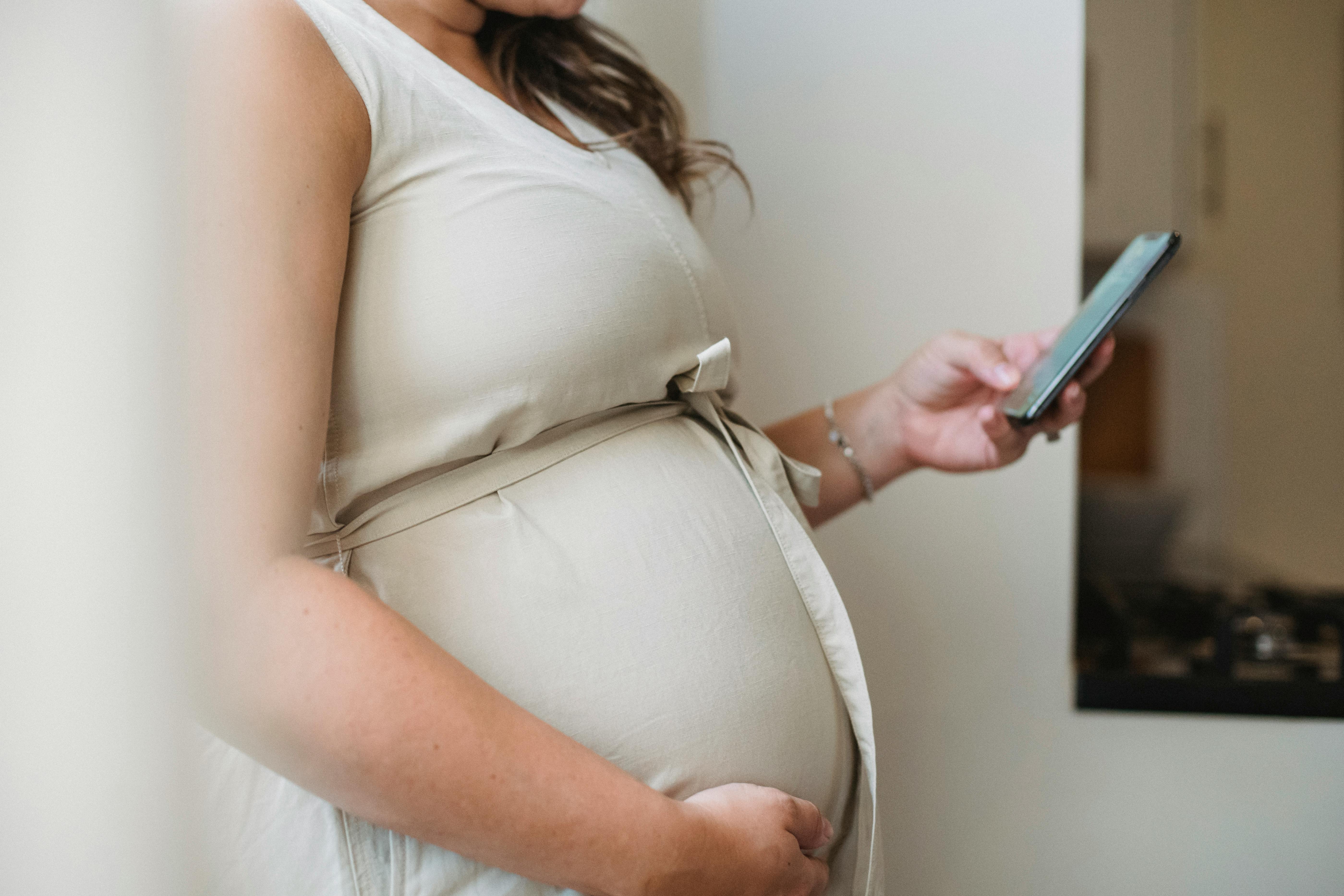 Una mujer embarazada usando su teléfono | Foto: Pexels