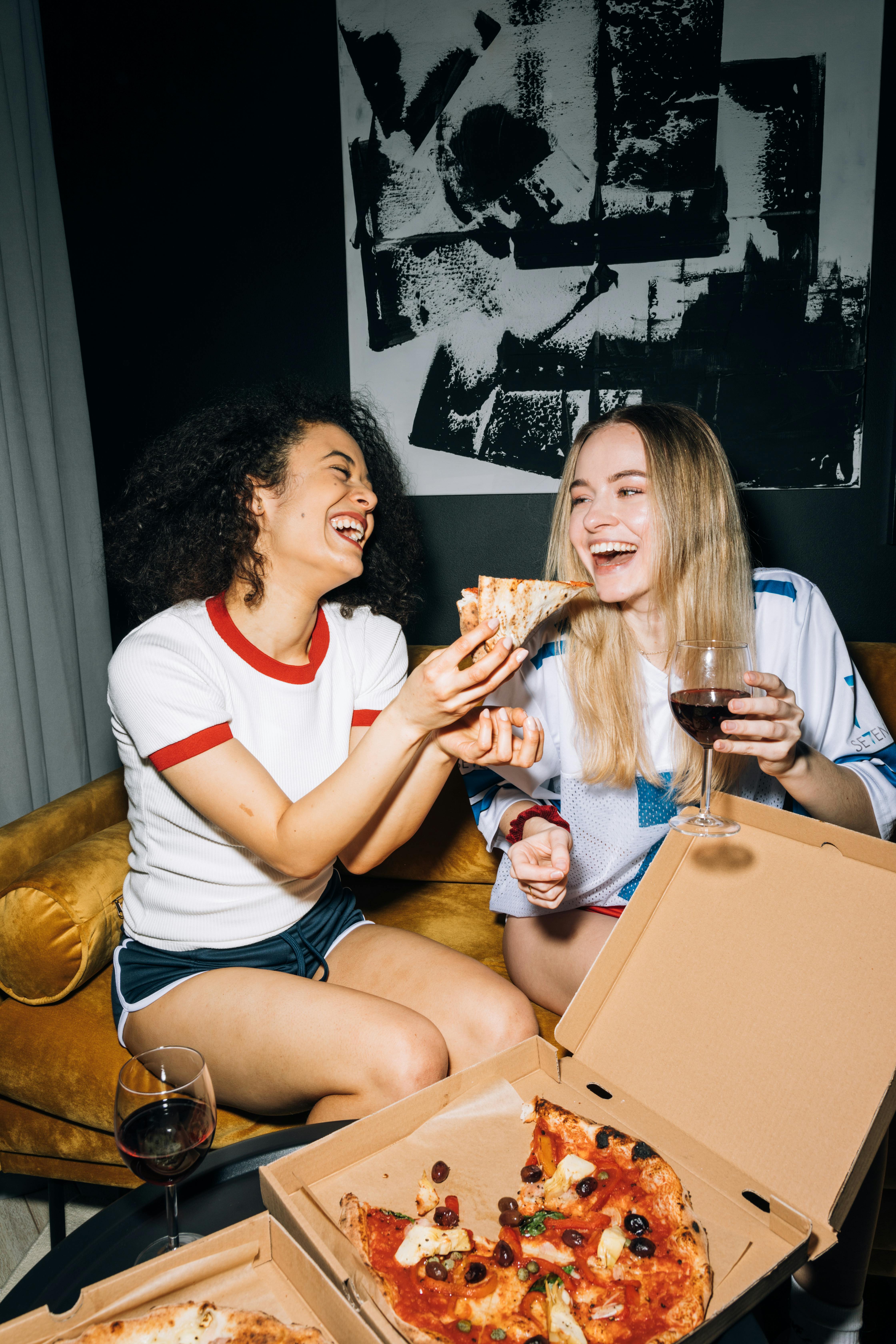 Mujeres disfrutando de pizza y vino | Fuente: Pexels