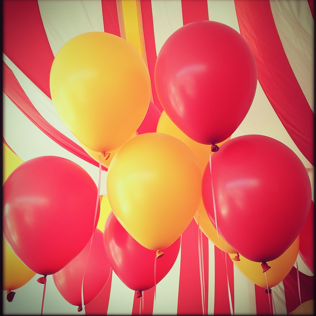 Globos rojos y amarillos en un baby shower con temática circense | Fuente: Midjourney