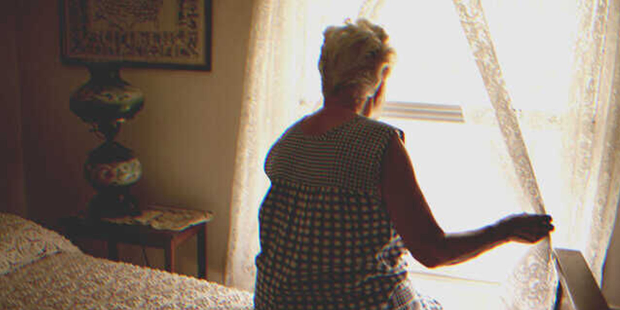 Una mujer mayor mira por una ventana | Foto: Getty Images