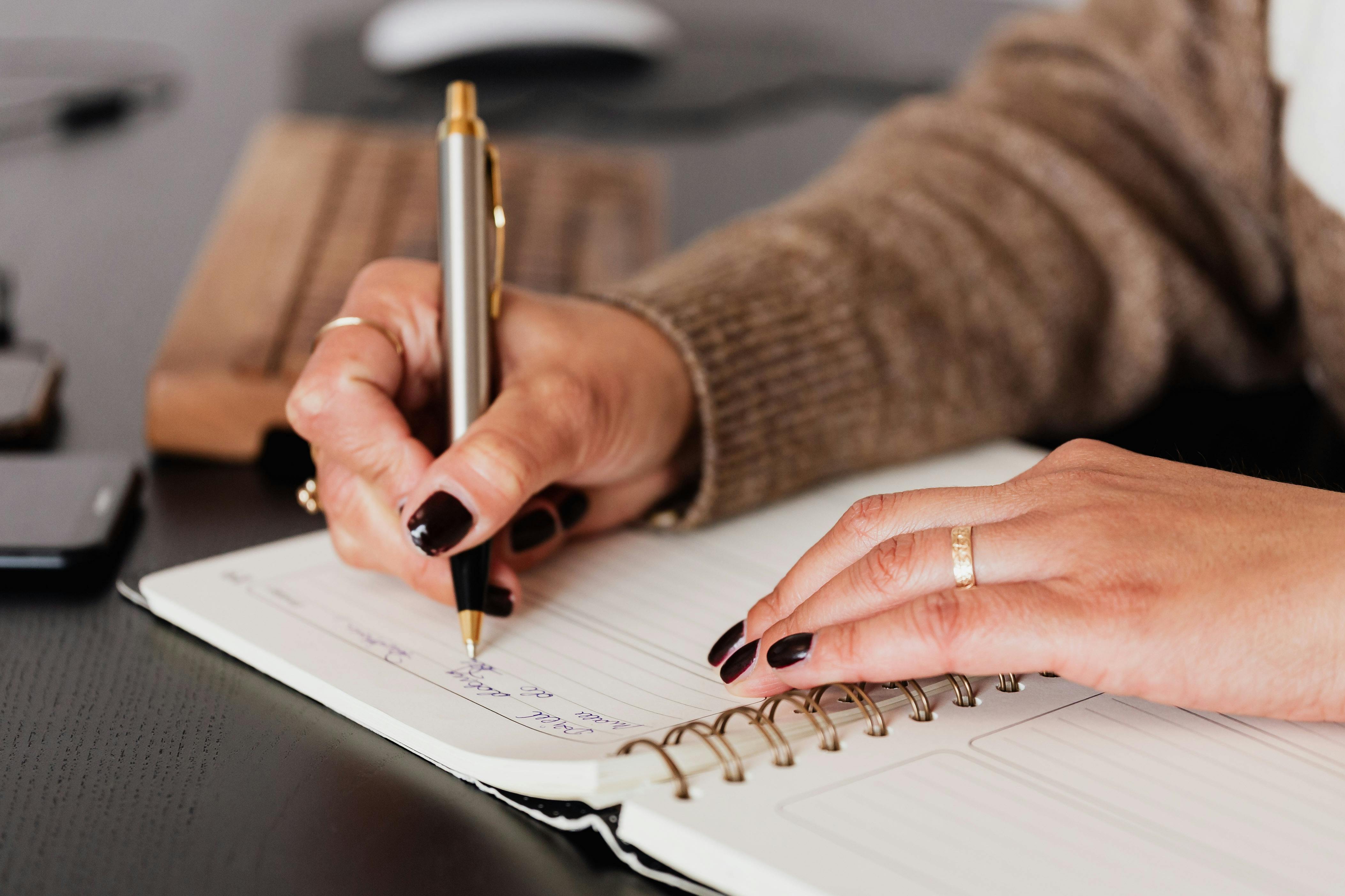 Una mujer escribiendo en un bloc de notas | Fuente: Pexels