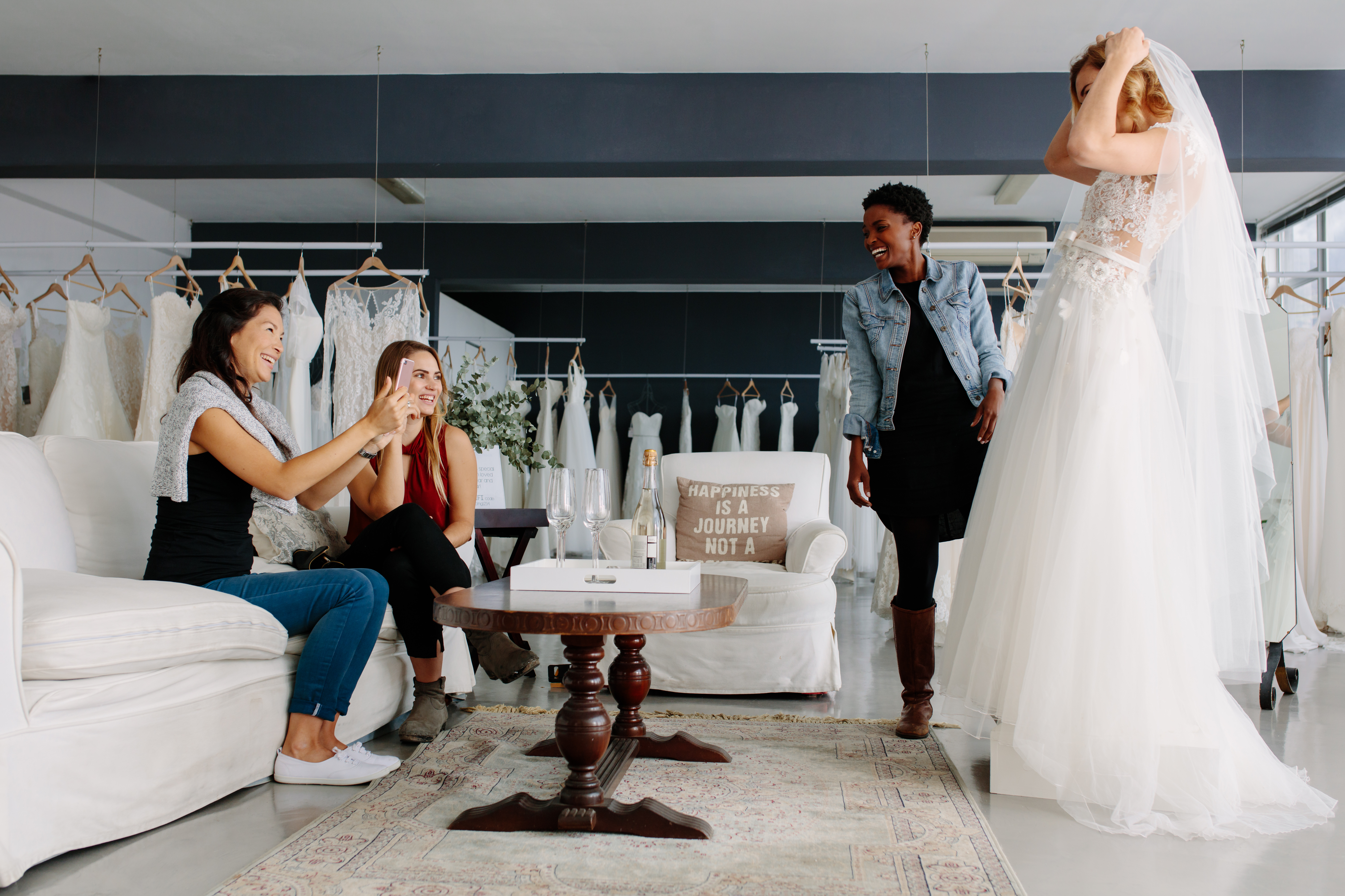 Una mujer probándose un vestido de novia rodeada de sus amigas | Foto: Shutterstock
