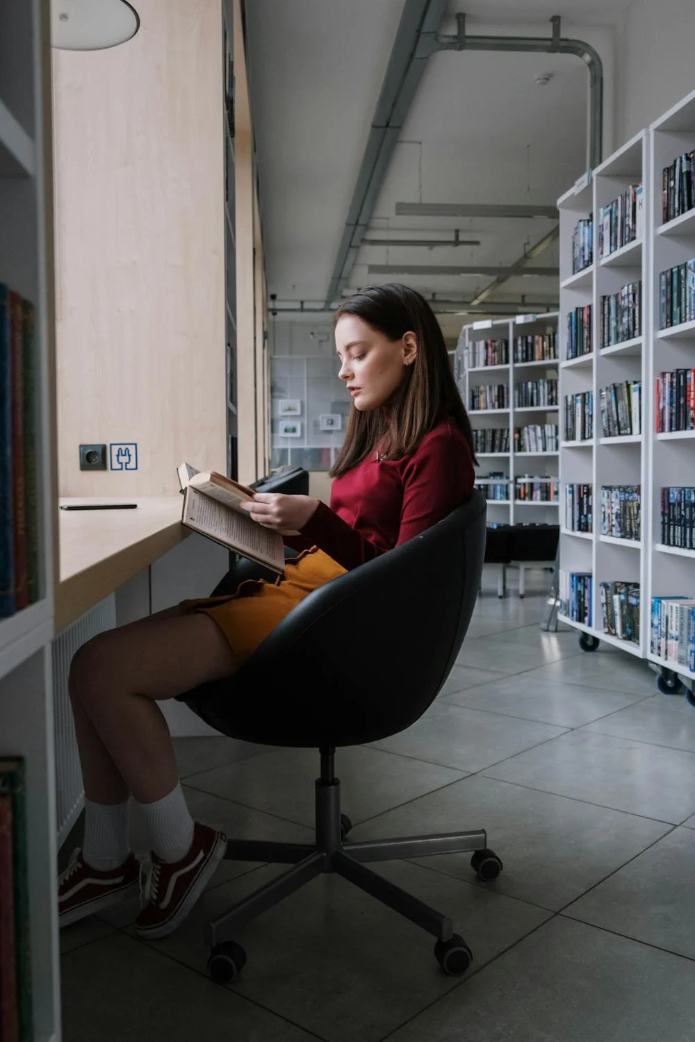 Una mujer leyendo en una biblioteca | Fuente: Pexels