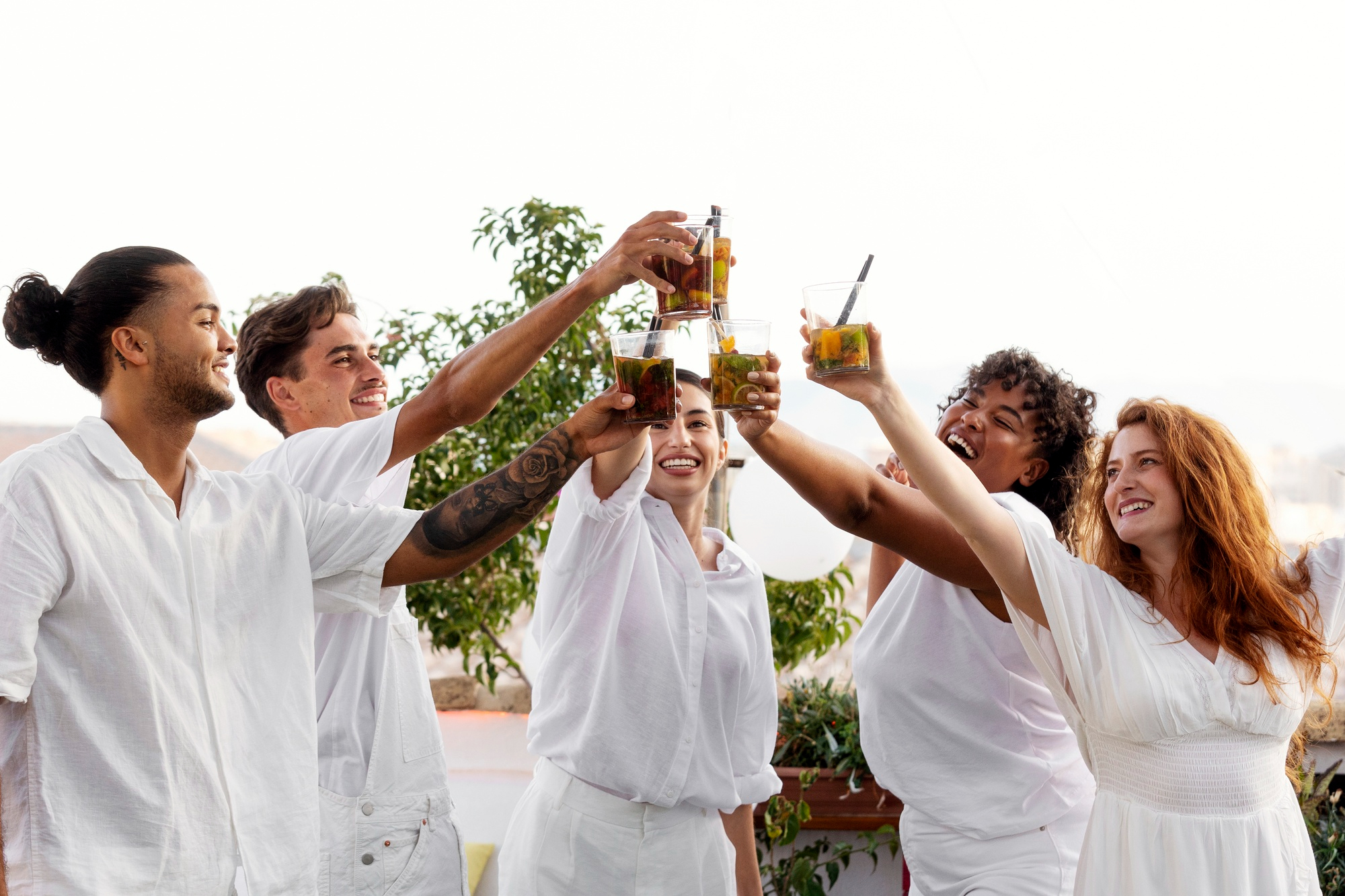 Gente vestida de blanco brindando en una fiesta | Fuente: Freepik