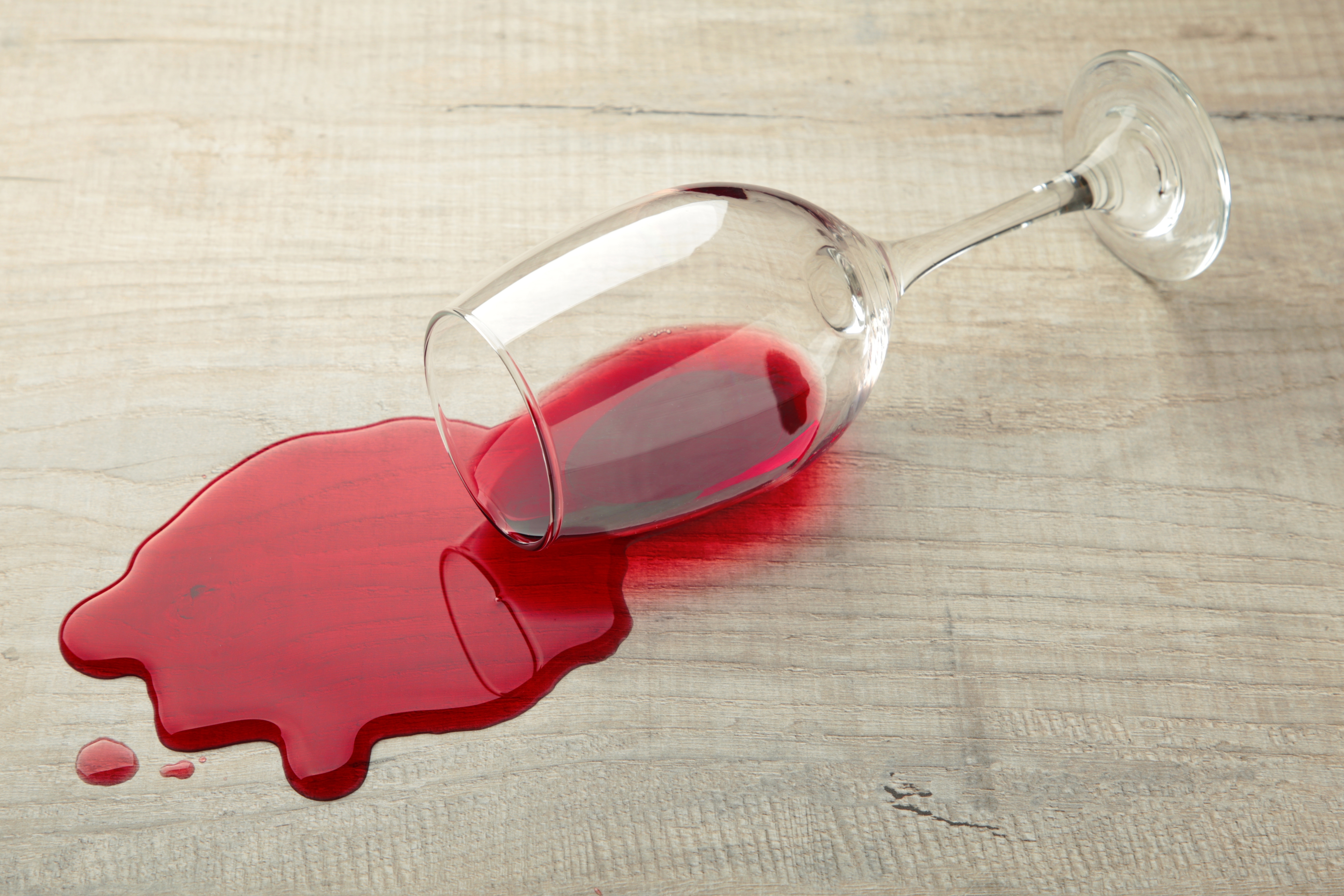 Un vaso de vino tinto cayó sobre el laminado, el vino se derramó por el suelo. | Fuente: Shutterstock