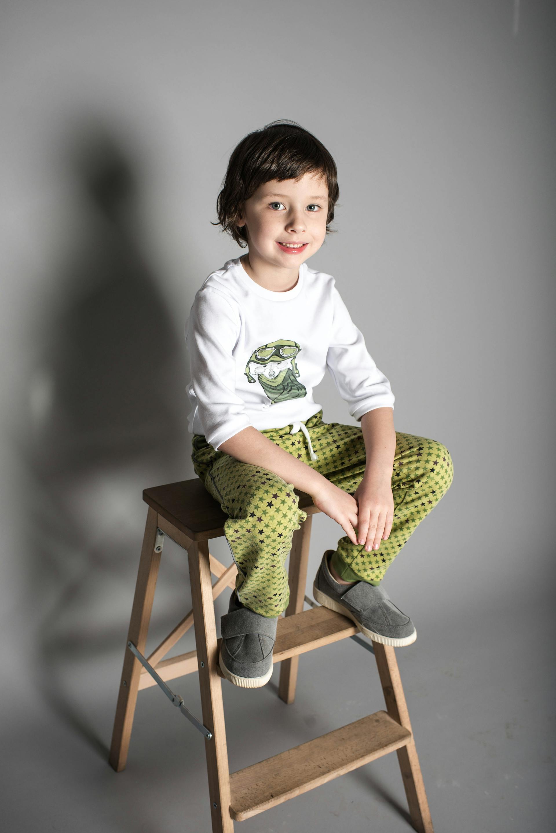 Un niño sentado en unos escalones de madera en forma de A | Fuente: Pexels